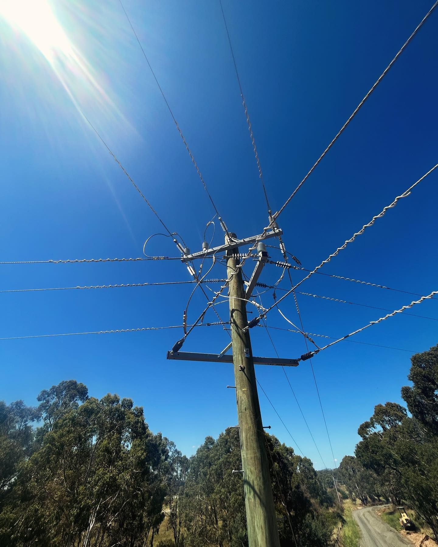 Power Lines Crisscross a Utility Pole Against a Bright Blue Sky — Central West Power Construction in Orange, NSW