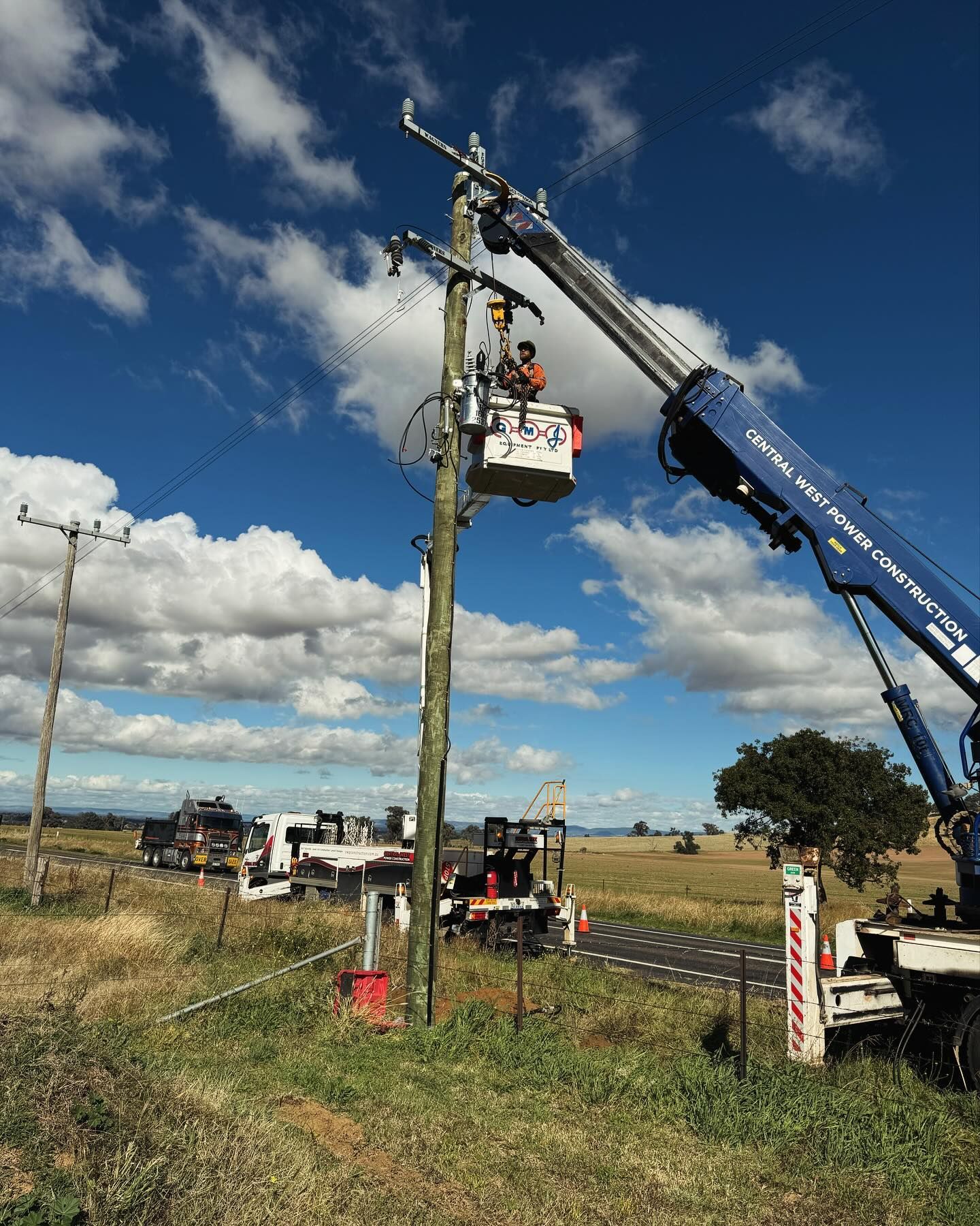 Linemen in a Bucket Truck Working on a Wooden Utility Pole in a Field — Central West Power Construction in Orange, NSW