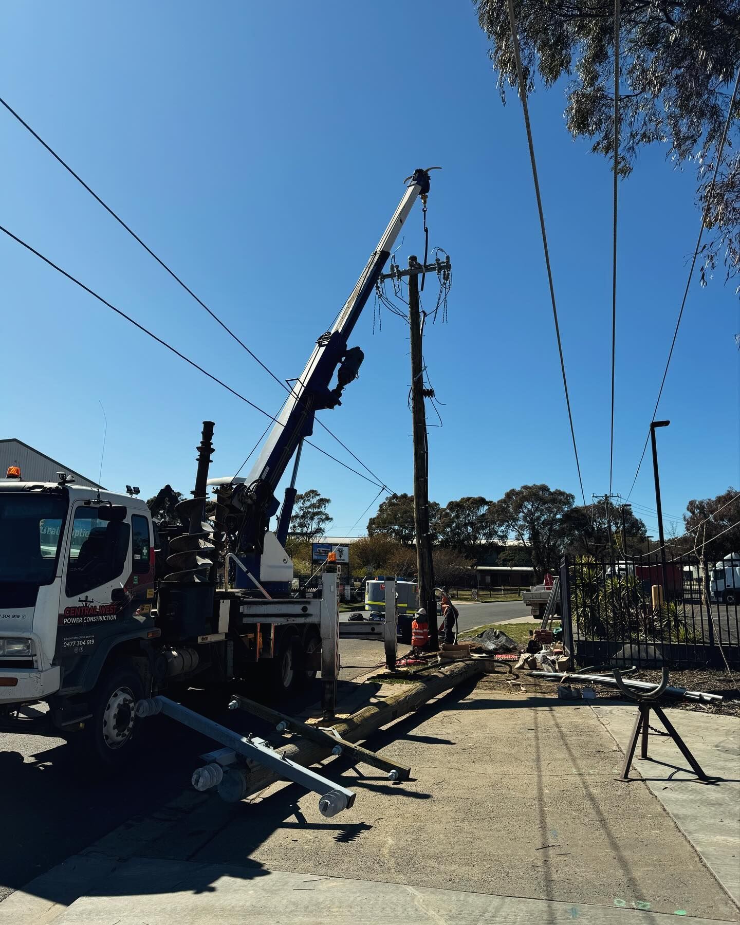 A Utility Truck With a Crane Working on Power Lines on a Sunny Day — Central West Power Construction in Orange, NSW
