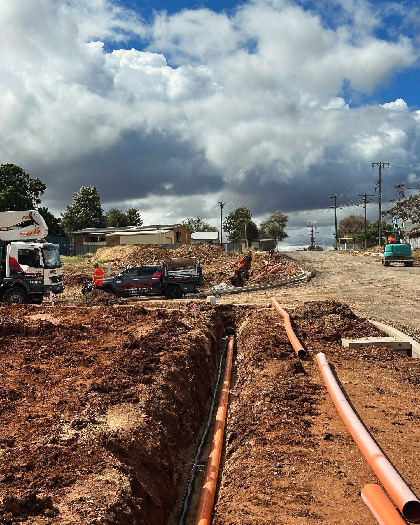 Construction Site With Trench, Orange Pipes, Trucks, Cloudy Sky — Central West Power Construction in Orange, NSW