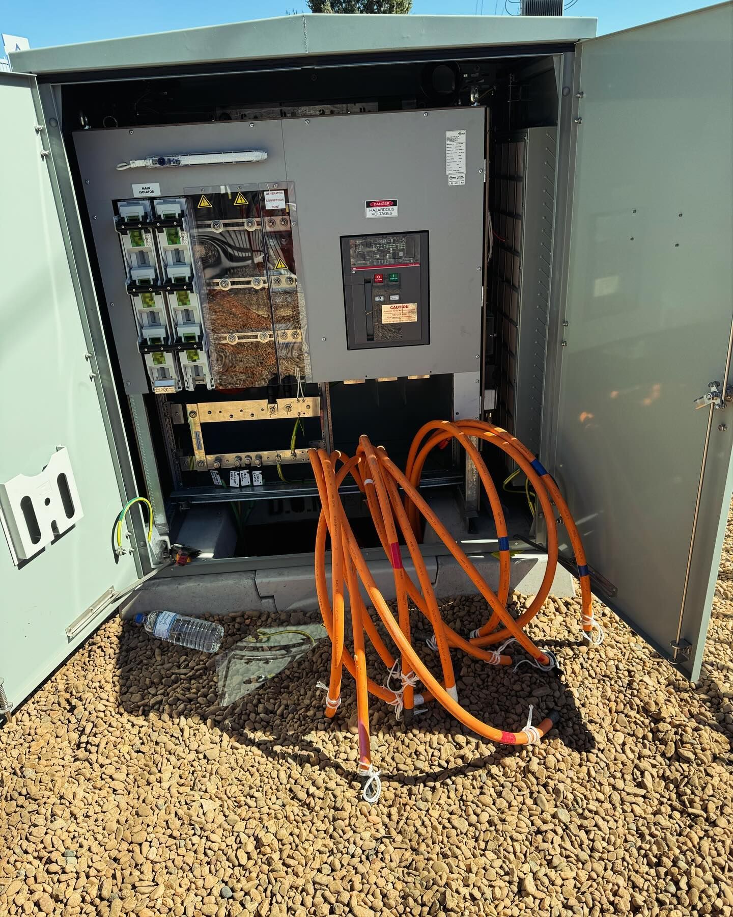 Outdoor Electrical Cabinet Open, Orange Cables Coiled, on Gravel — Central West Power Construction in Orange, NSW