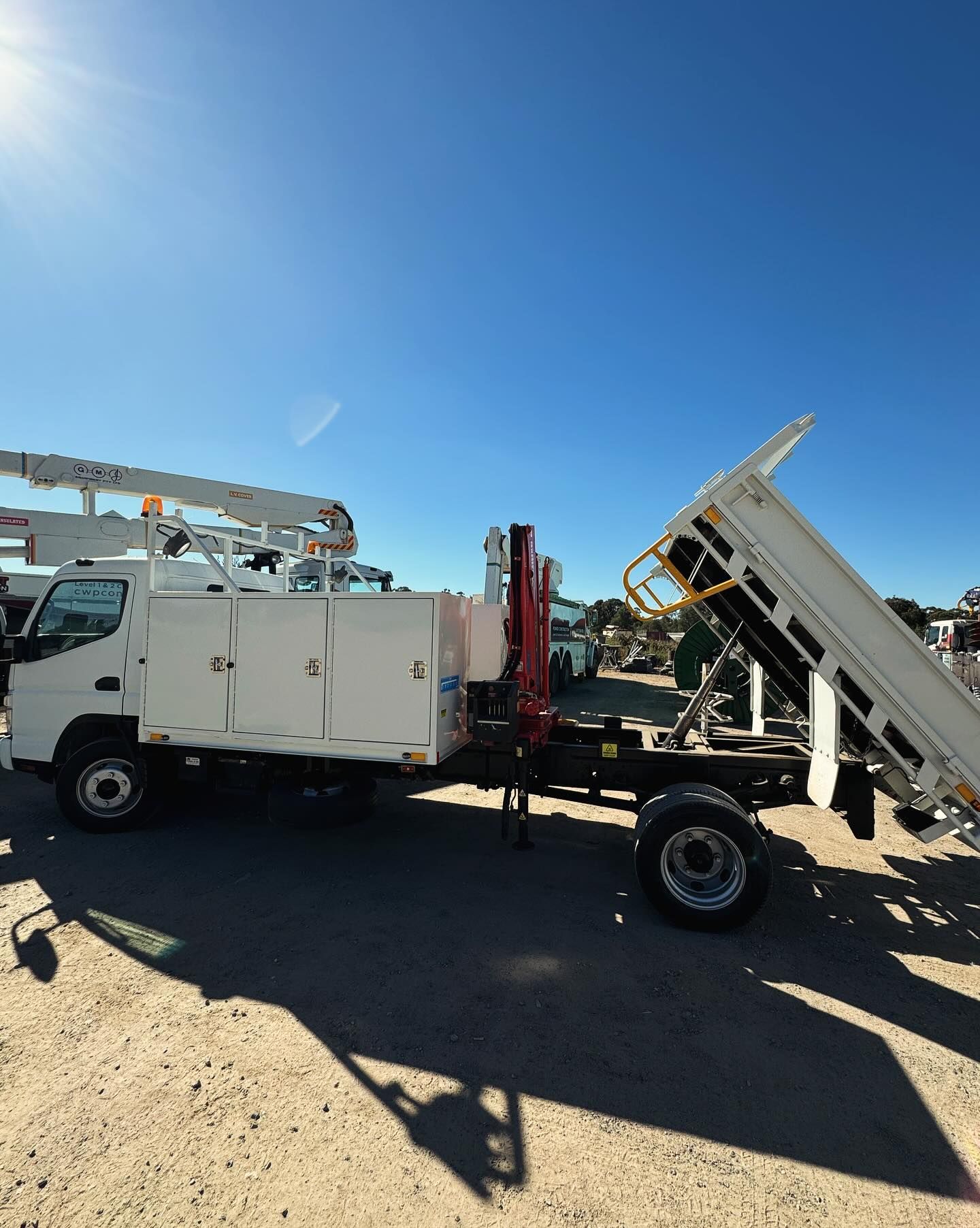 White Utility Truck With an Open Dump Bed and Crane, Parked on a Dirt — Central West Power Construction in Orange, NSW