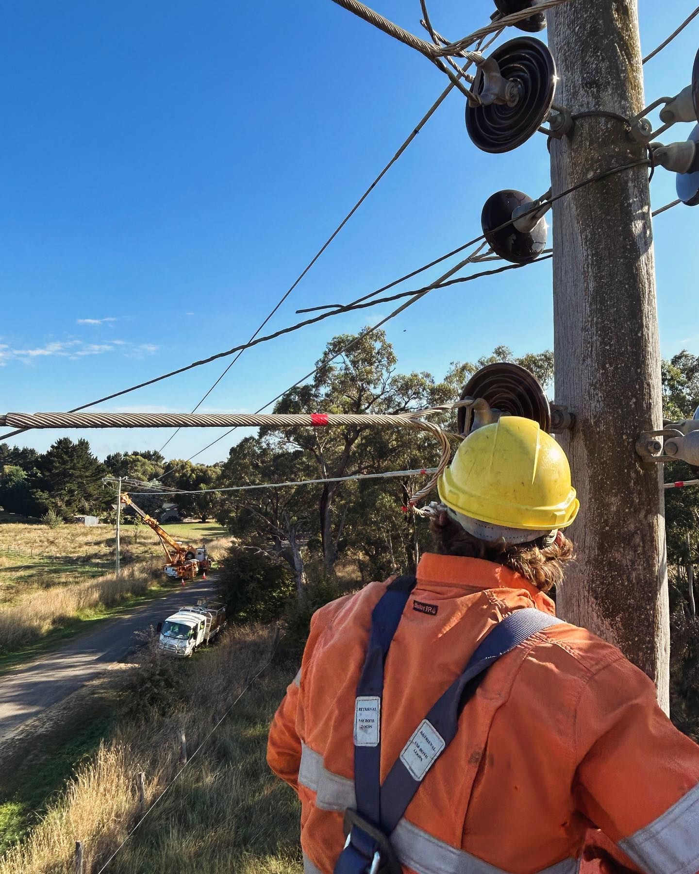 Lineman in Orange Gear Inspects Power Lines on a Utility Pole — Central West Power Construction in Orange, NSW