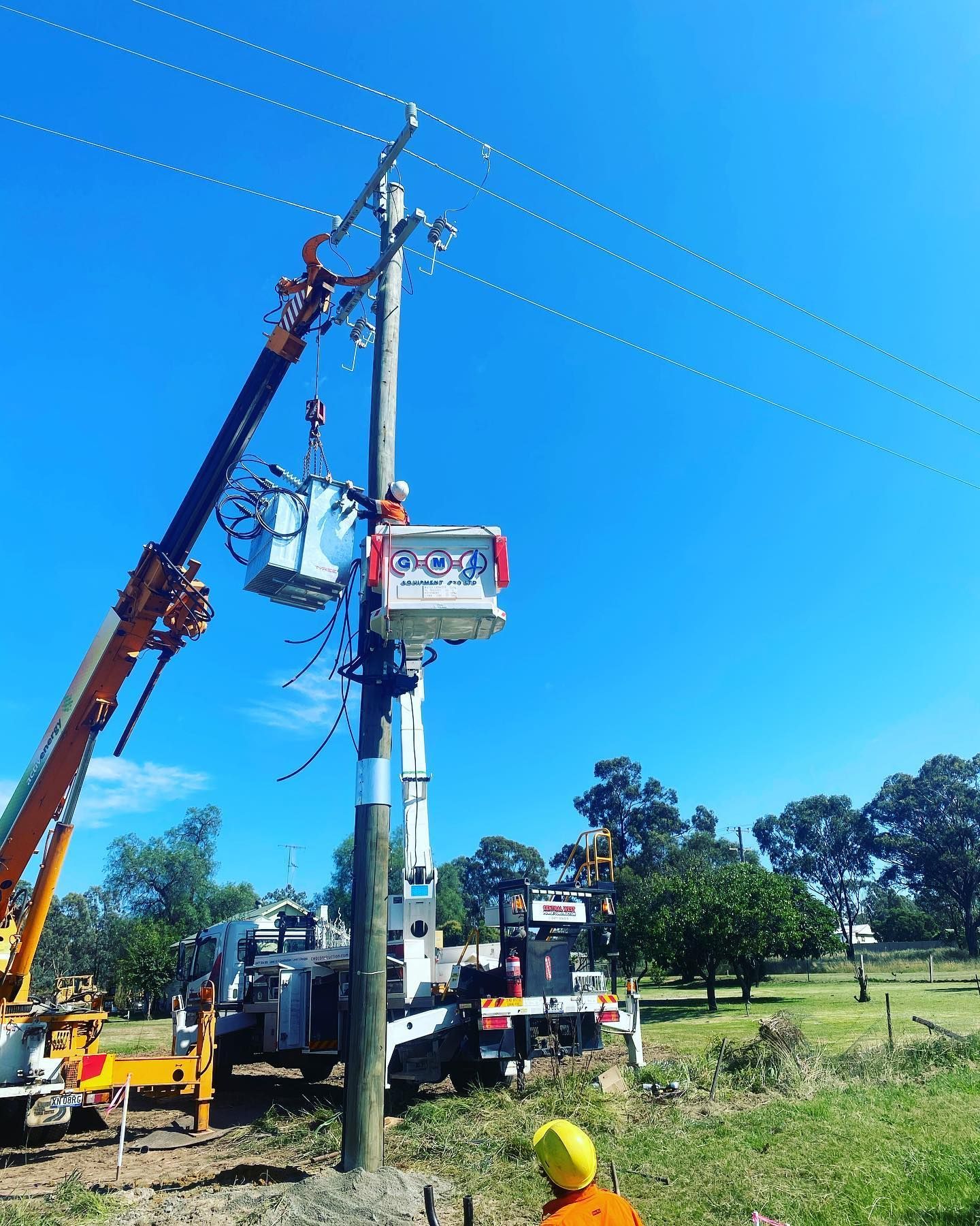 Linemen Working on a Power Pole With Bucket Trucks Under a Bright Blue Sky — Central West Power Construction in Orange, NSW
