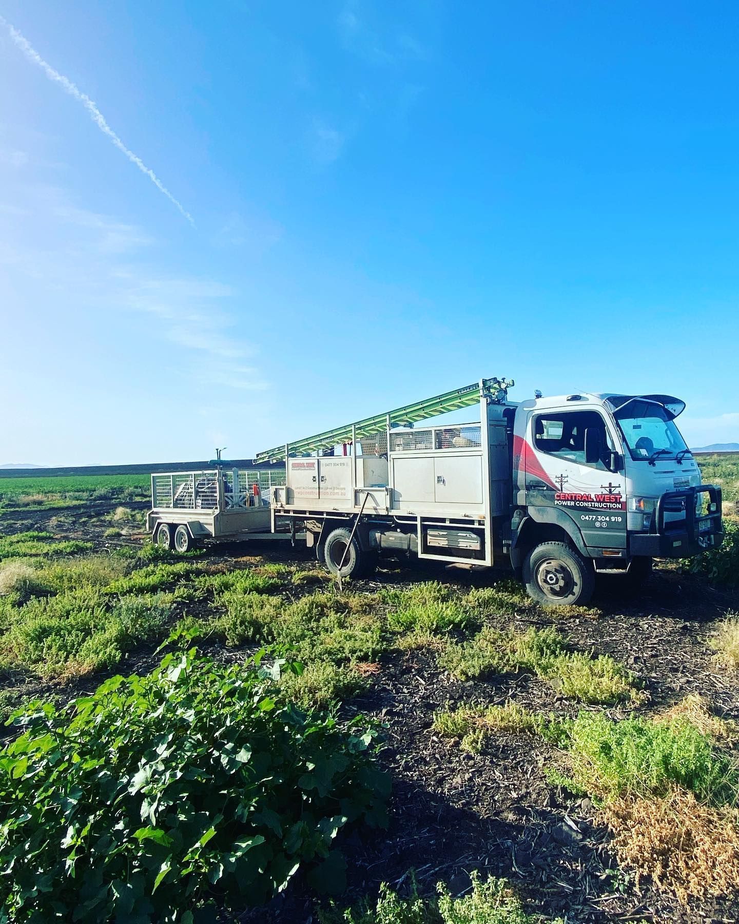 Truck With Trailer Parked in Field Under Blue Sky — Central West Power Construction in Orange, NSW