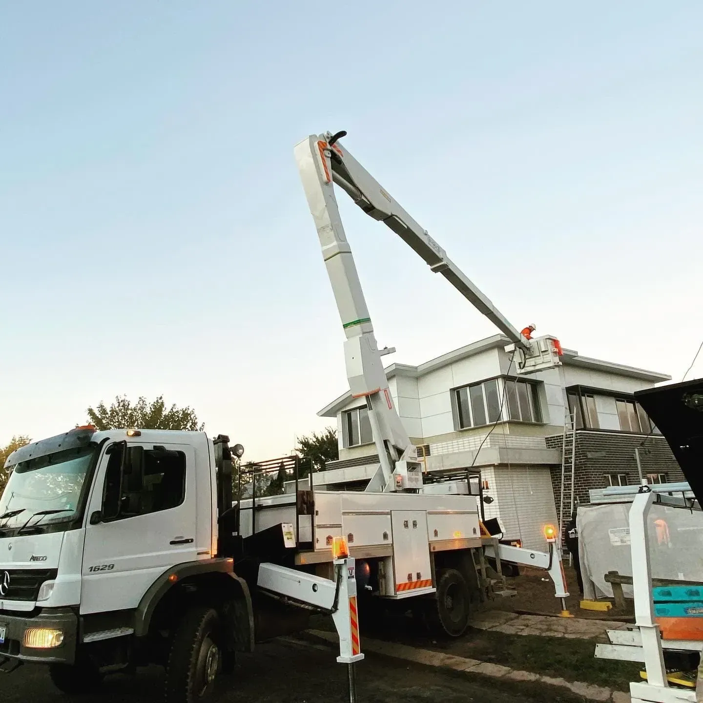 White Truck With an Aerial Lift Reaching Towards a House; Construction Site — Central West Power Construction in Orange, NSW