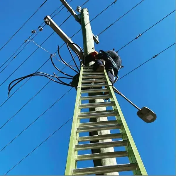 Lineman on a Ladder Working on Utility Pole With Wires and Street Light — Central West Power Construction in Orange, NSW