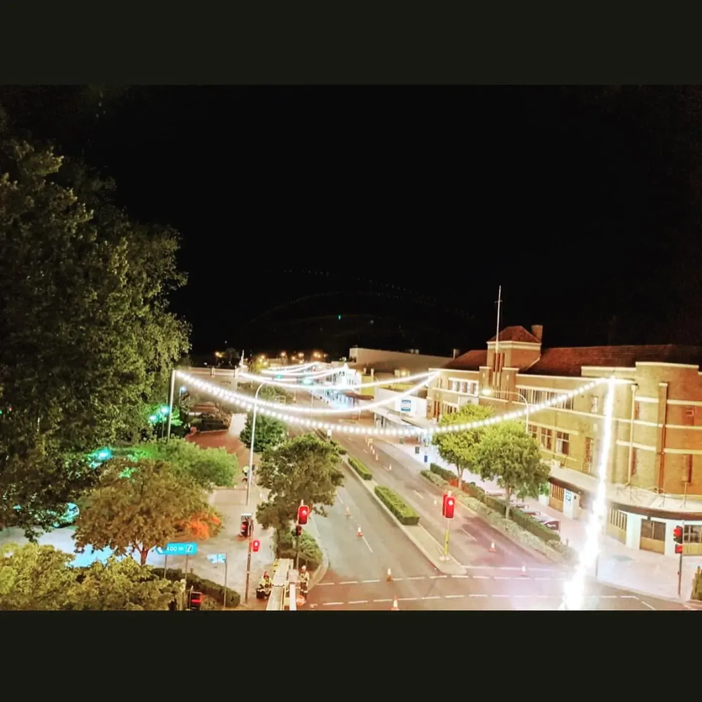 Night View of a Street With Strung Lights, Trees, and a Brick Building — Central West Power Construction in Orange, NSW