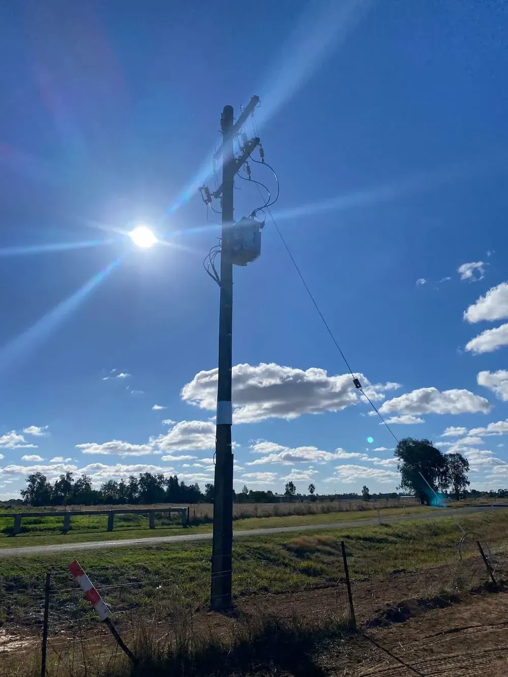 Sun Shining Behind a Power Pole With a Transformer — Central West Power Construction in Orange, NSW