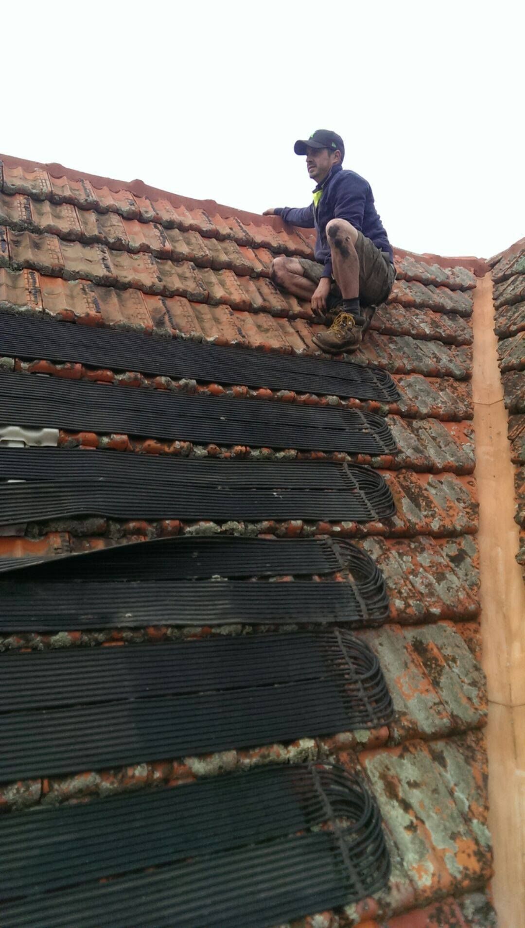 A man is sitting on top of a tiled roof.