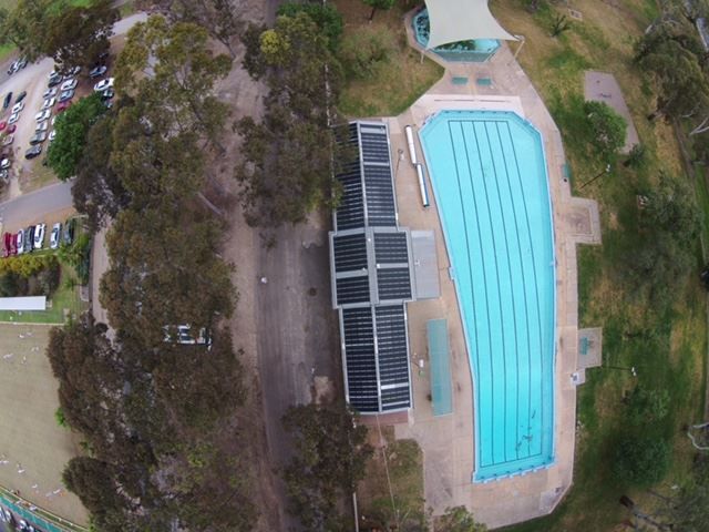 An aerial view of a large swimming pool surrounded by trees.