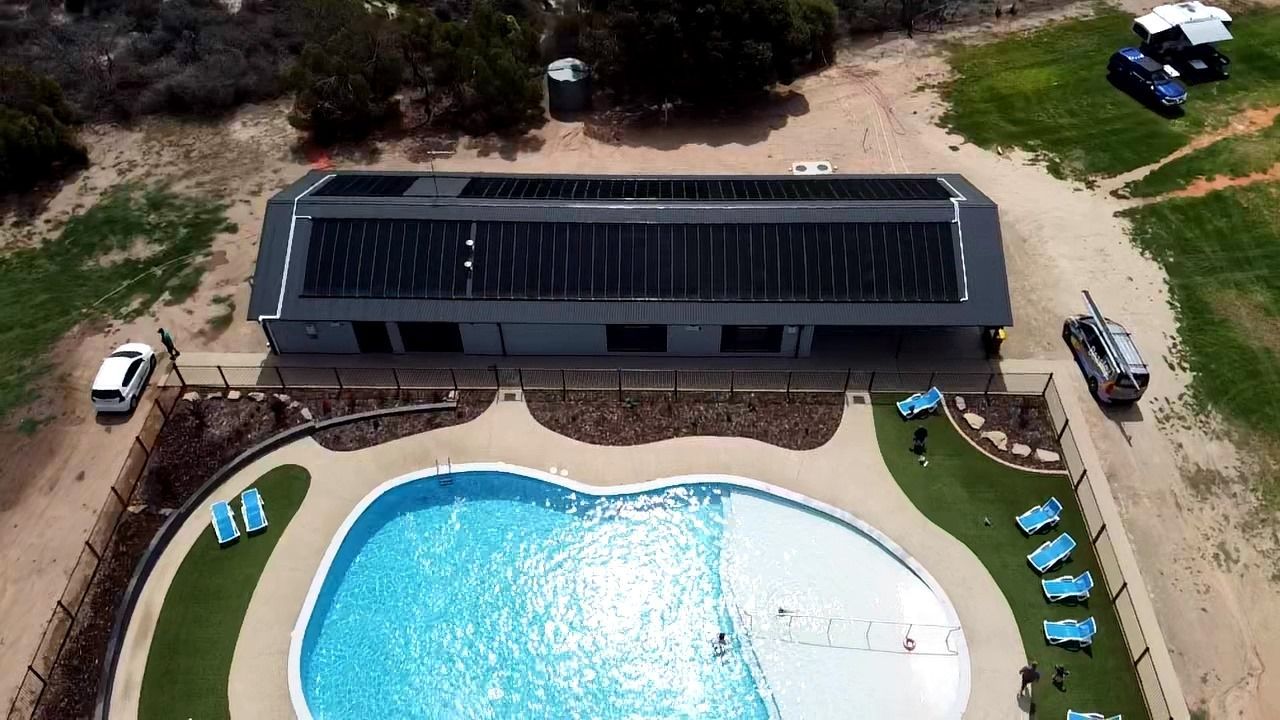 An aerial view of a large swimming pool with solar panels on the roof