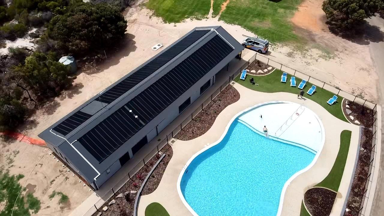 An aerial view of a swimming pool with solar panels on the roof