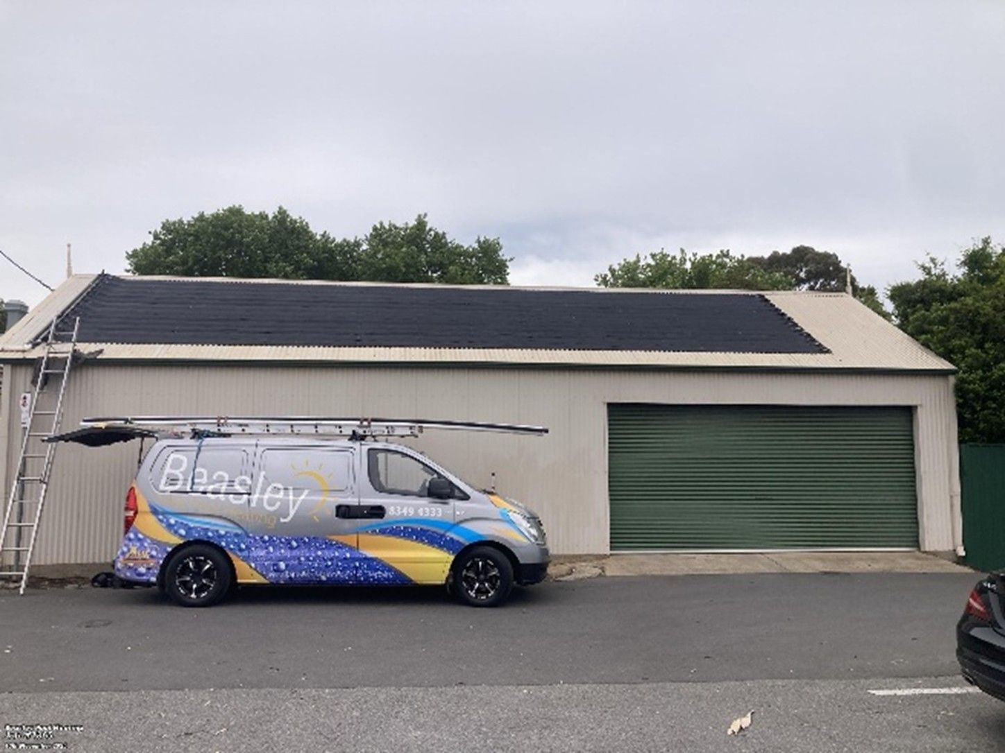 A Beasley Pool Heating van parked in front of a garage with a solar panel installed on its roof.