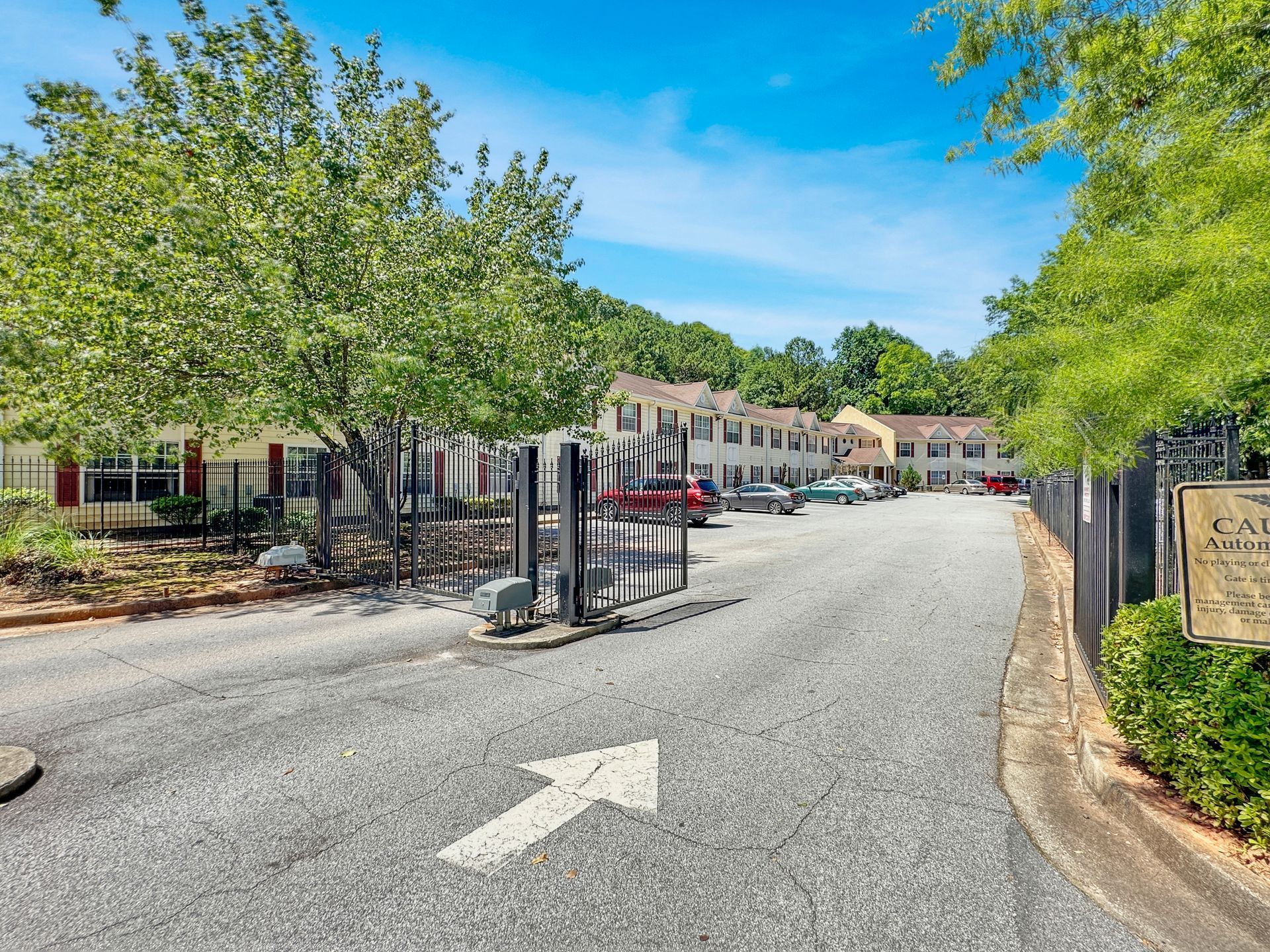 A parking lot with cars parked in front of a building and a fence.
