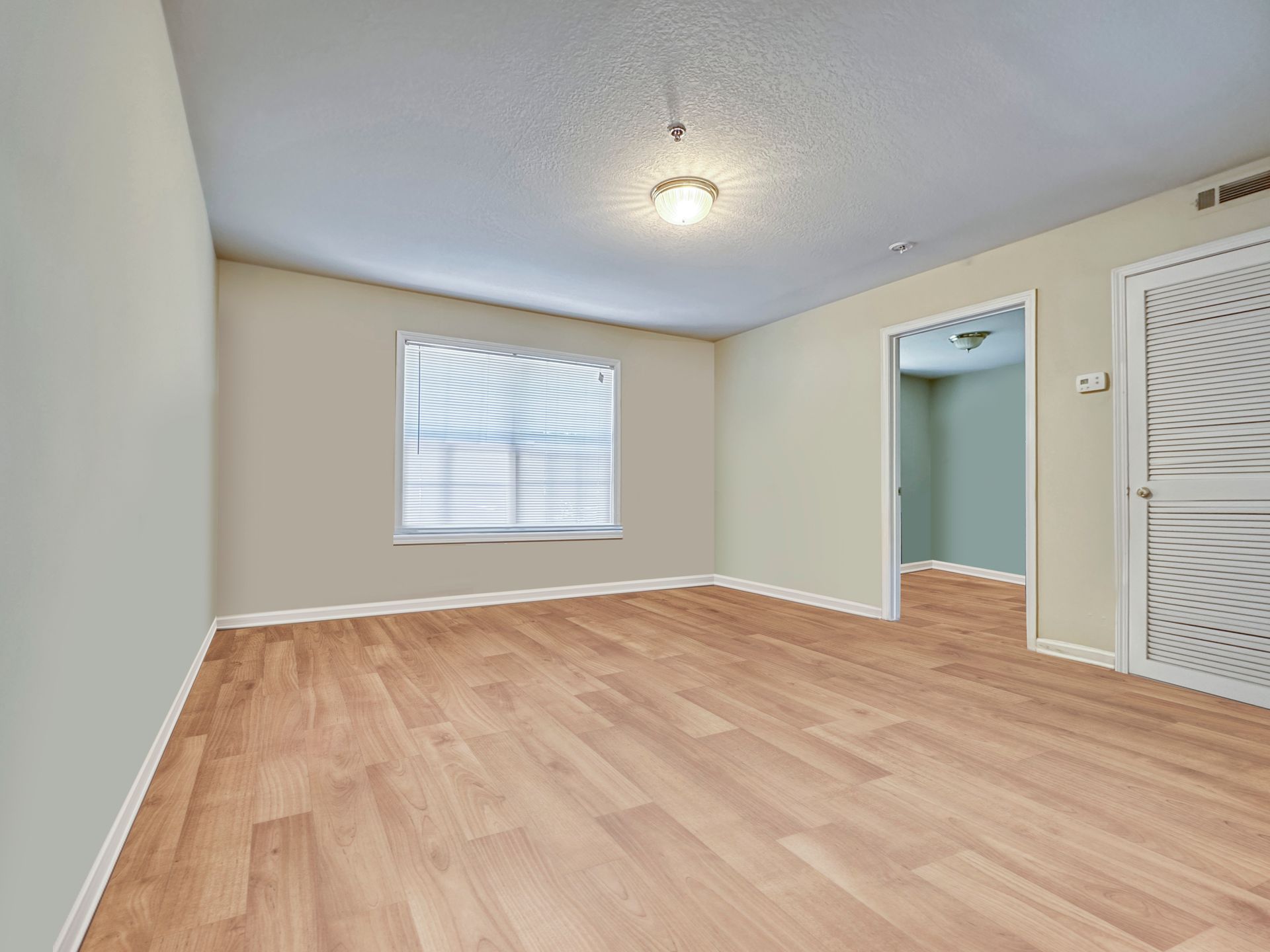 An empty room with hardwood floors and a window.