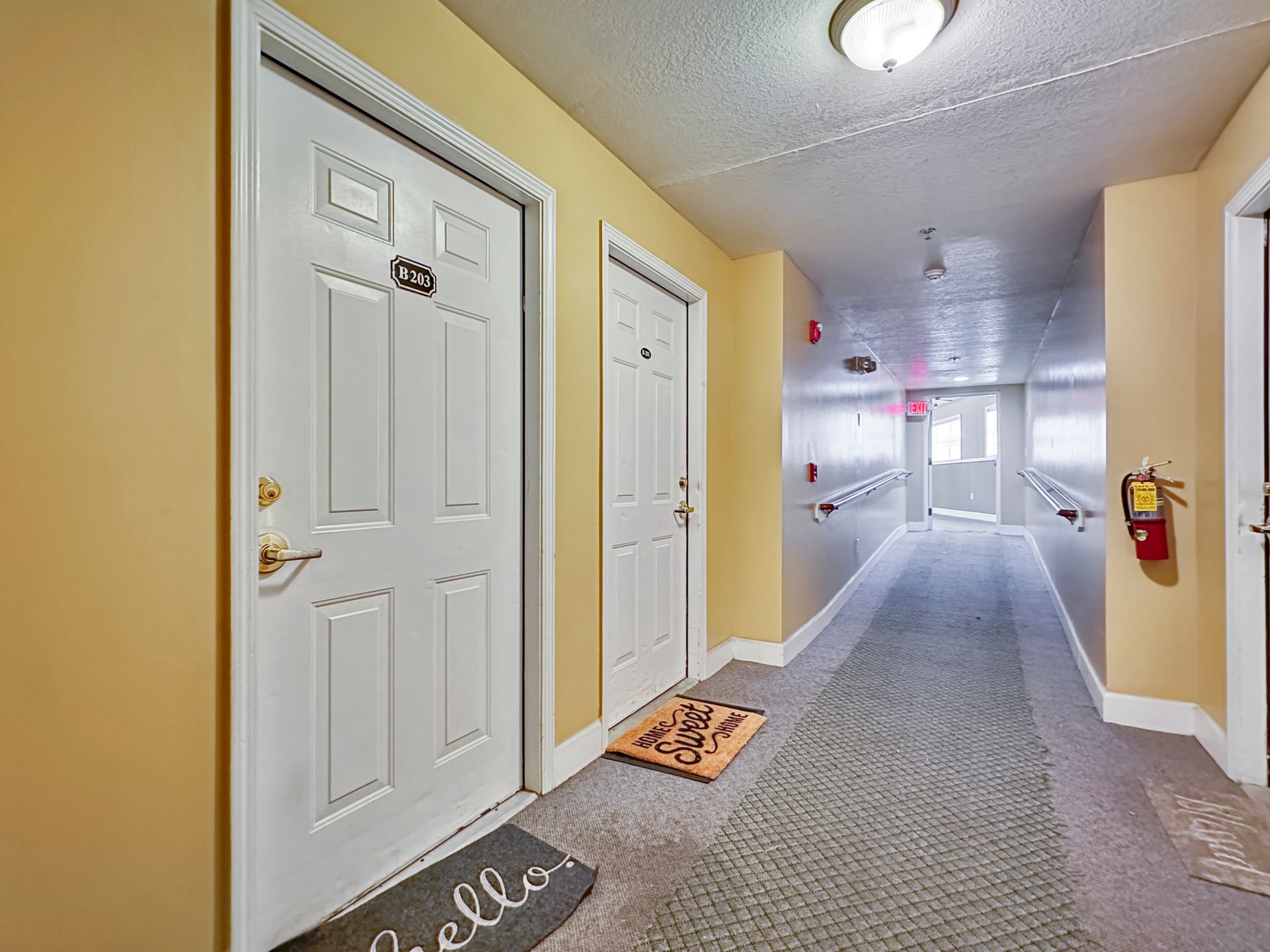 A hallway with white doors and a welcome mat on the floor.
