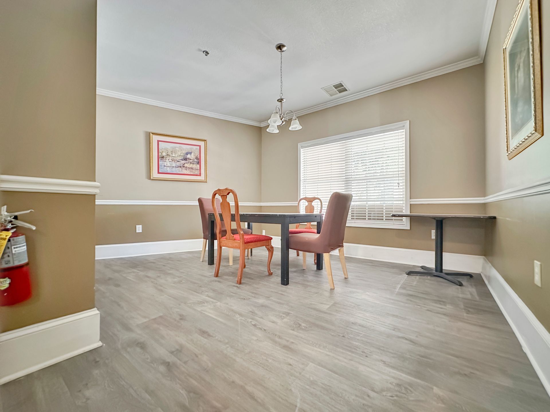 A dining room with a table and chairs and a fire extinguisher.