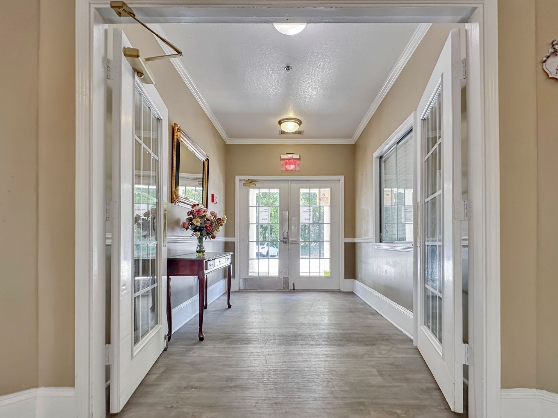 A long hallway with french doors and a table in the middle.