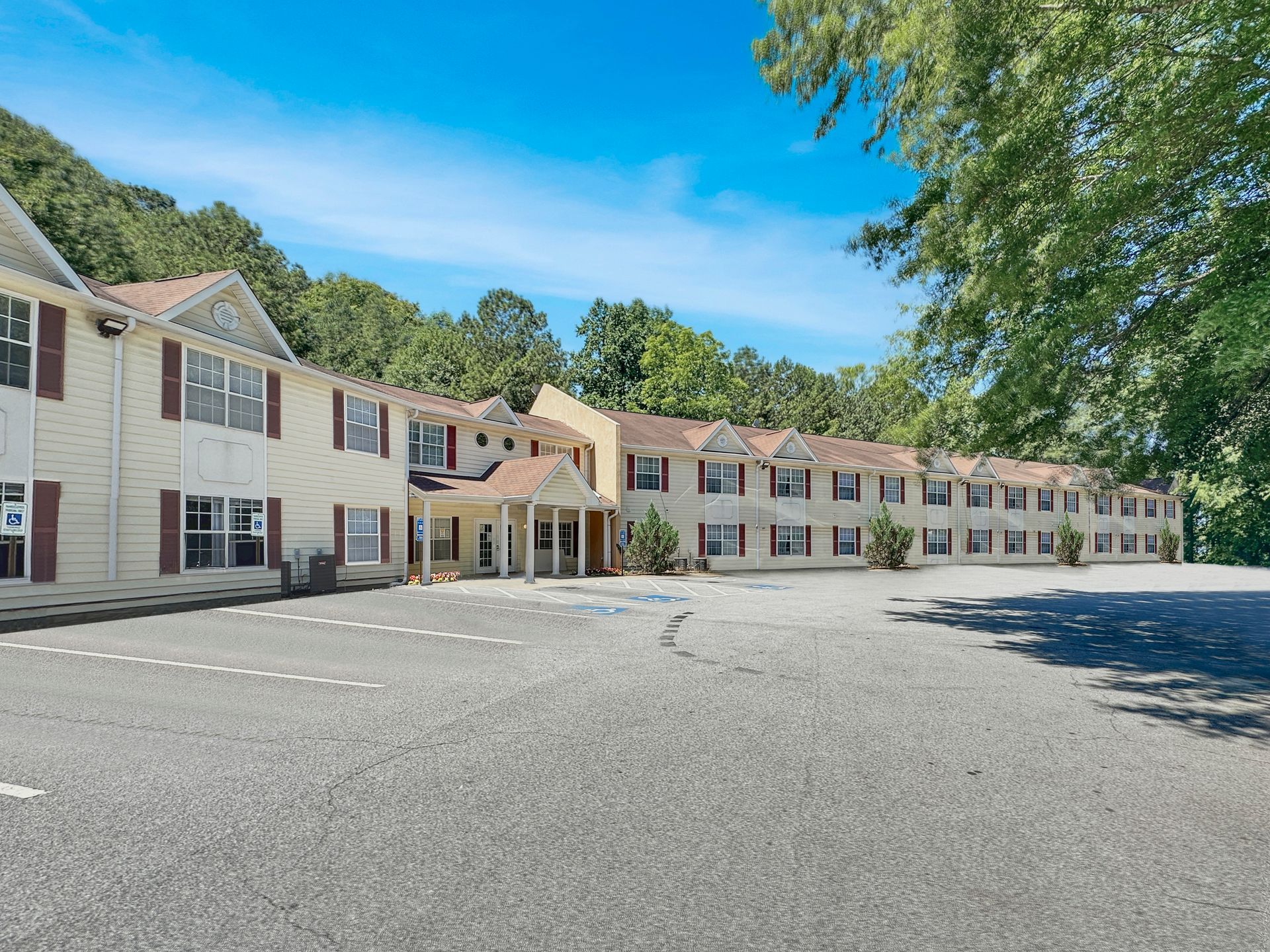 A large apartment building with a lot of windows and a parking lot in front of it.