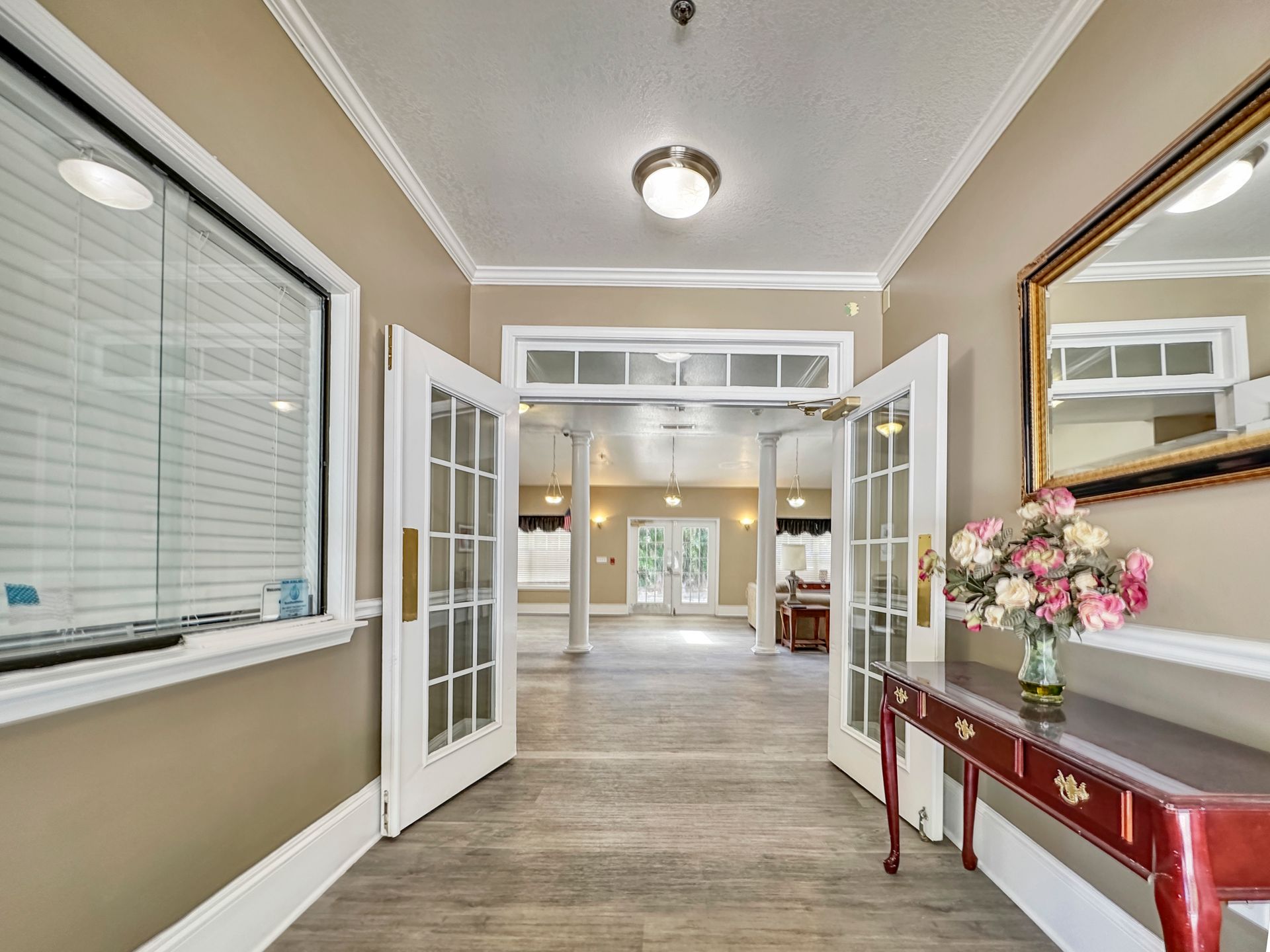 There is a table with flowers on it in the hallway.