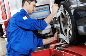Mechanic checking wheel alignment on a car