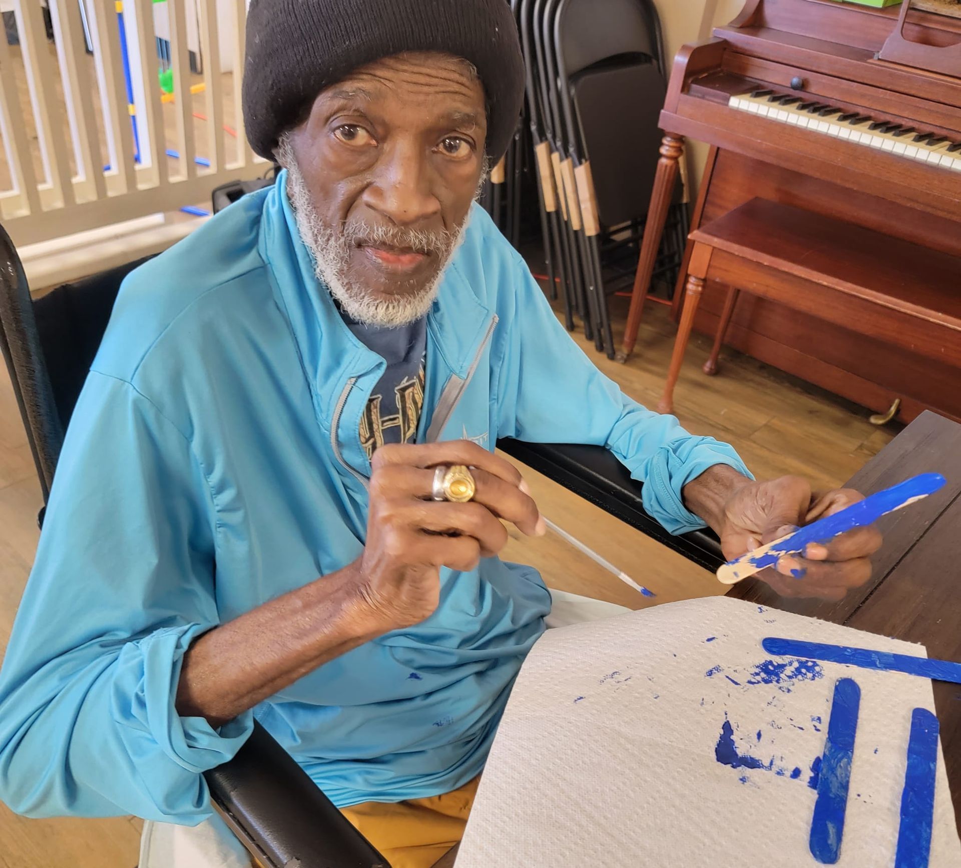 A man in a wheelchair is painting a picture with a blue brush