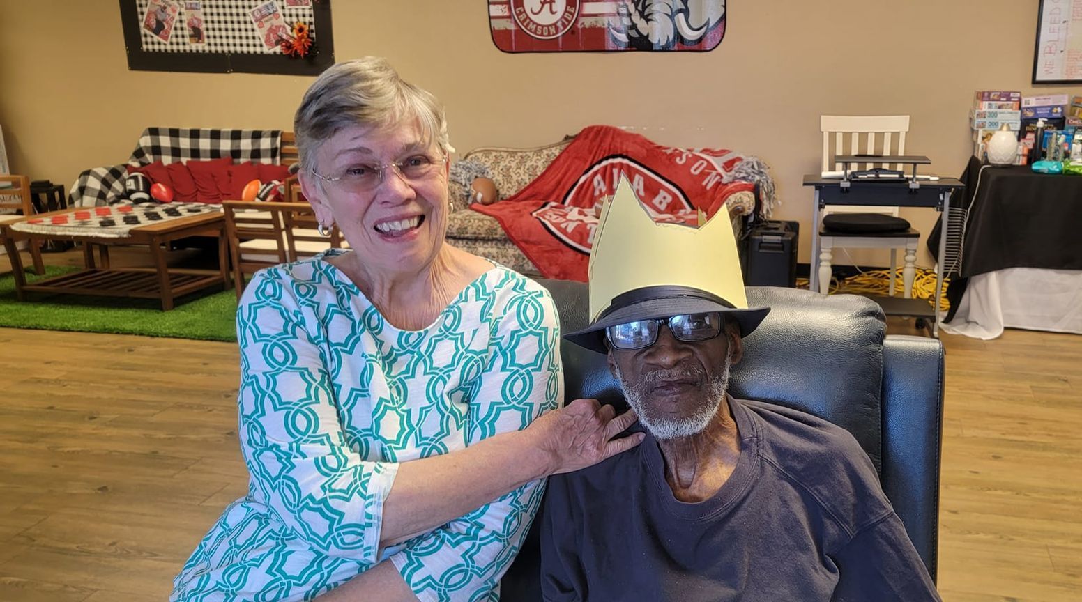 A woman is putting a crown on a man 's head.
