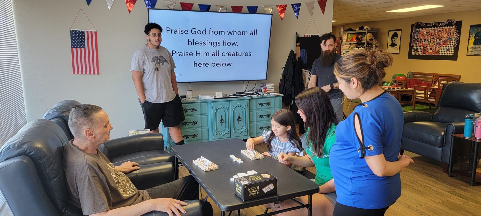 A group of people are sitting around a table in a living room.