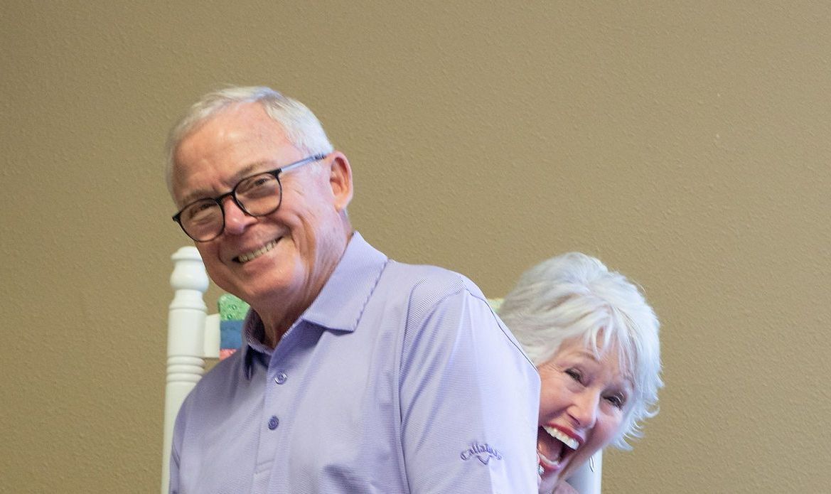 A man and a woman are standing next to each other and smiling.