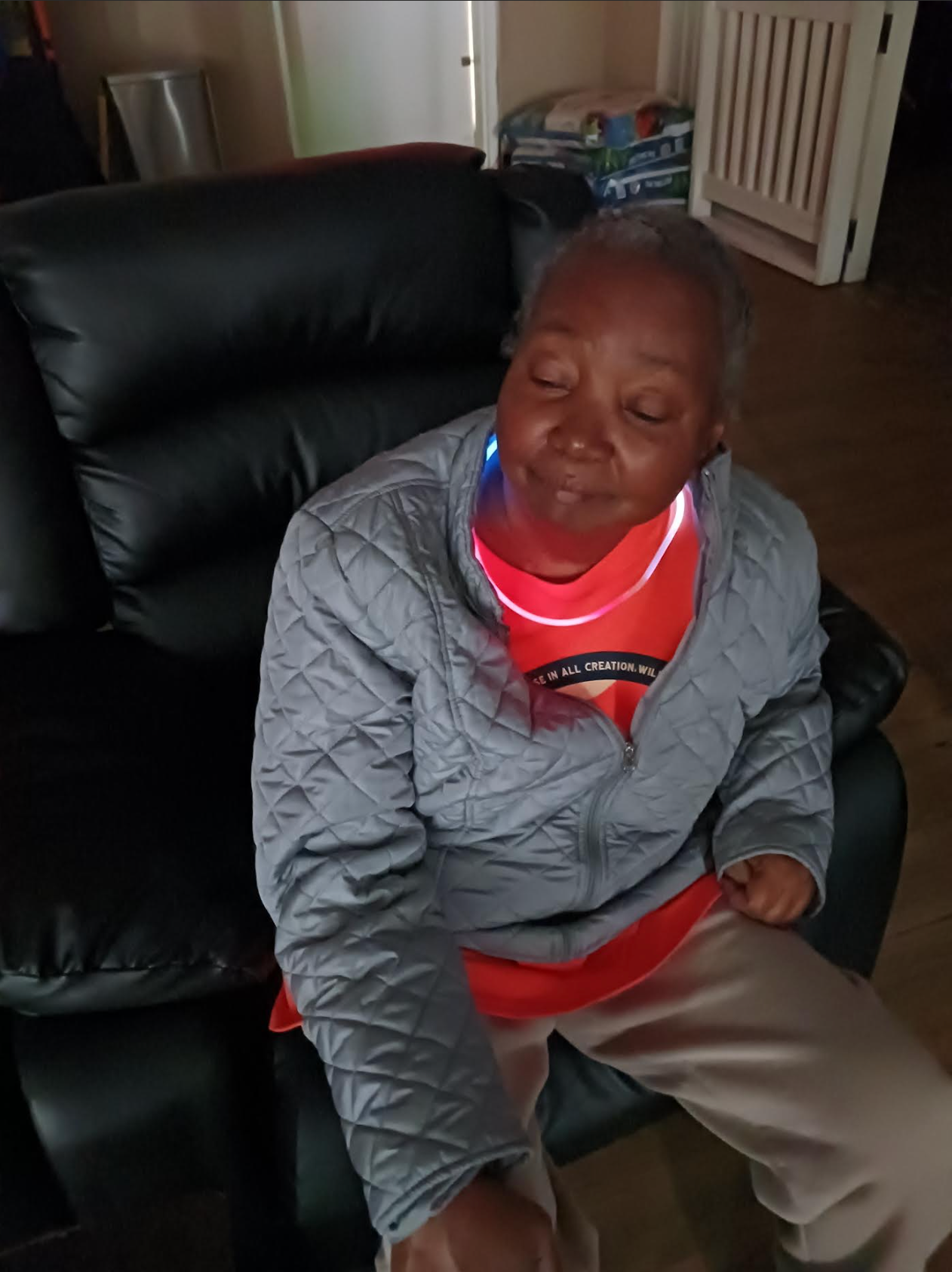An elderly woman is sitting in a chair with her eyes closed.