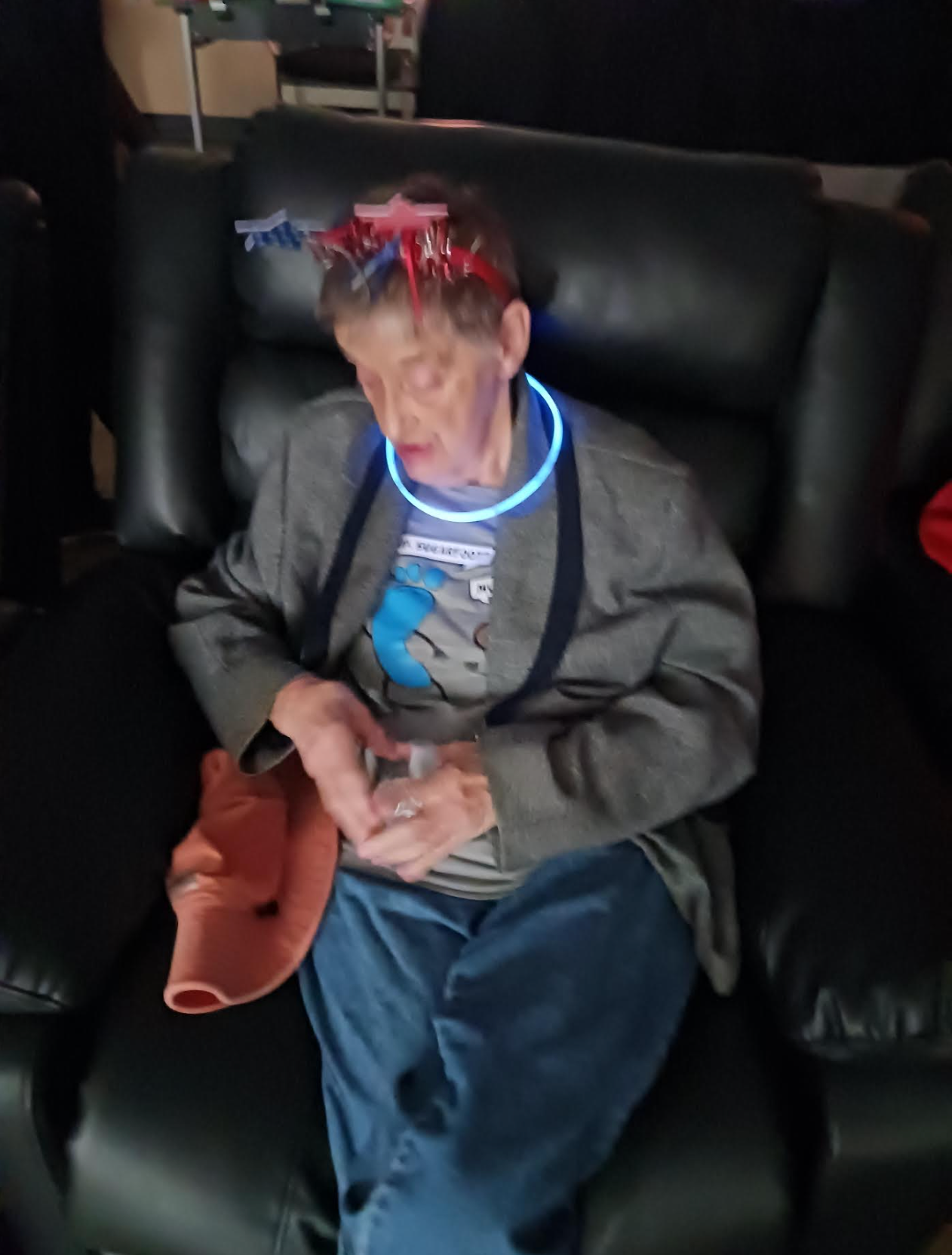 A man wearing a neon necklace is sitting on a couch