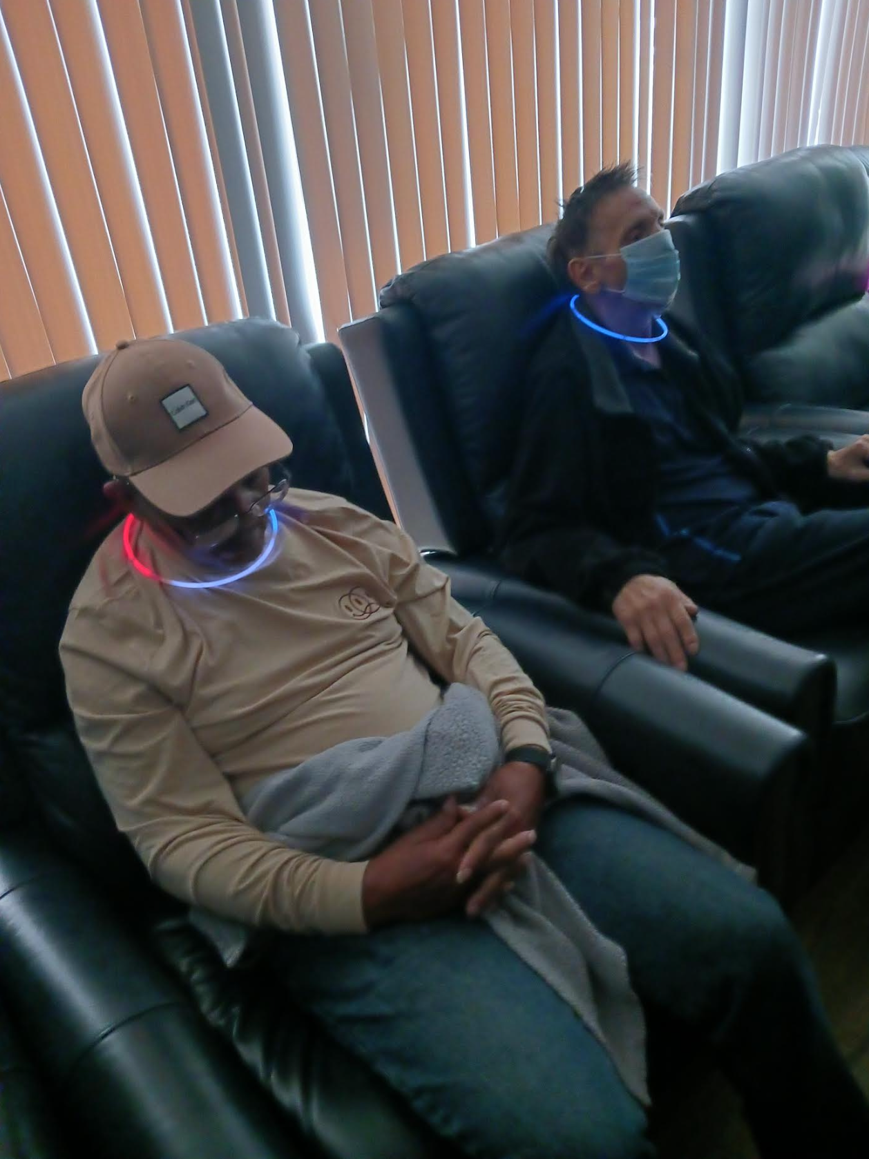 Two men wearing face masks are sitting in chairs