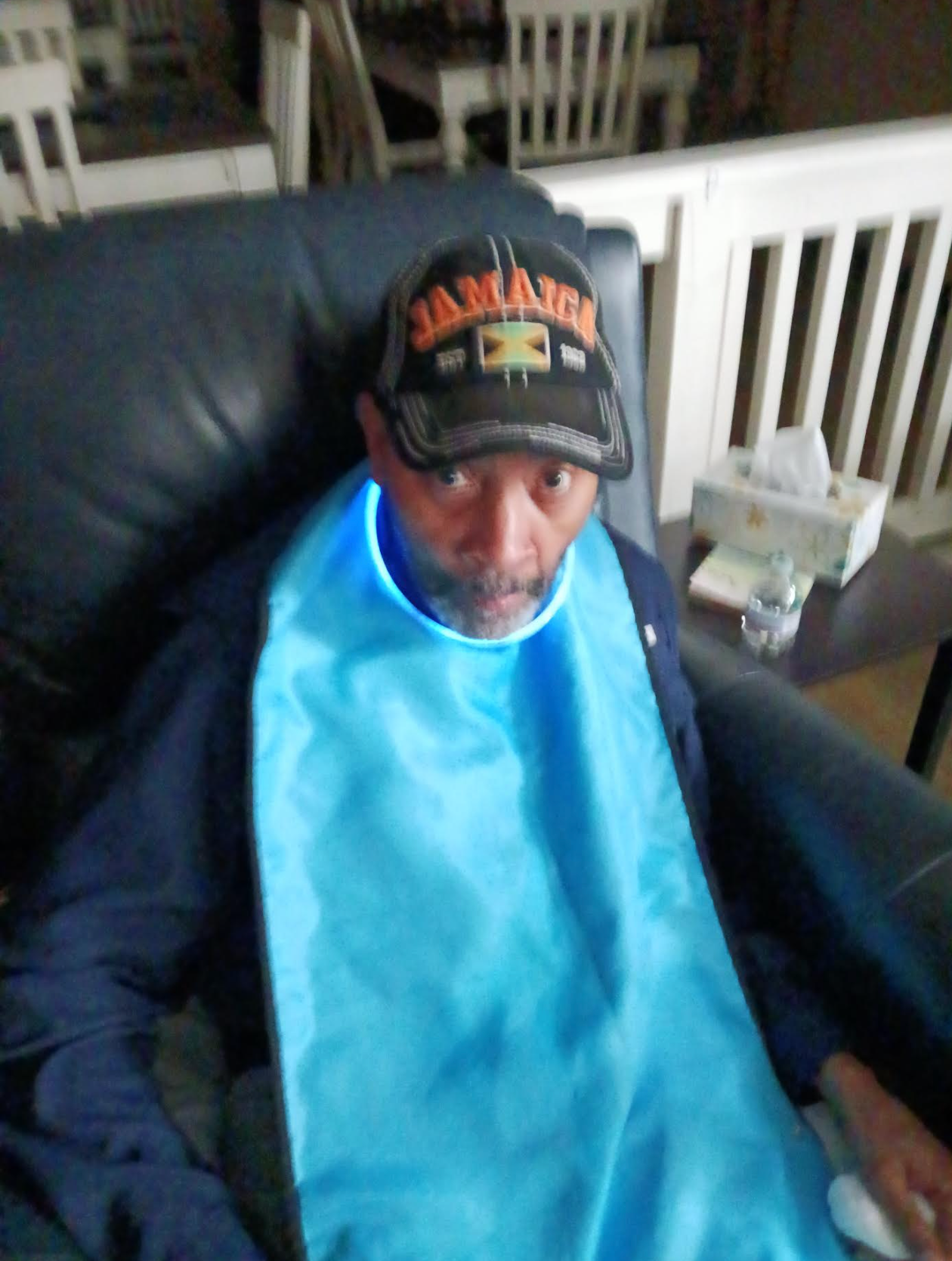 A man wearing a hat that says jamaica is sitting in a chair