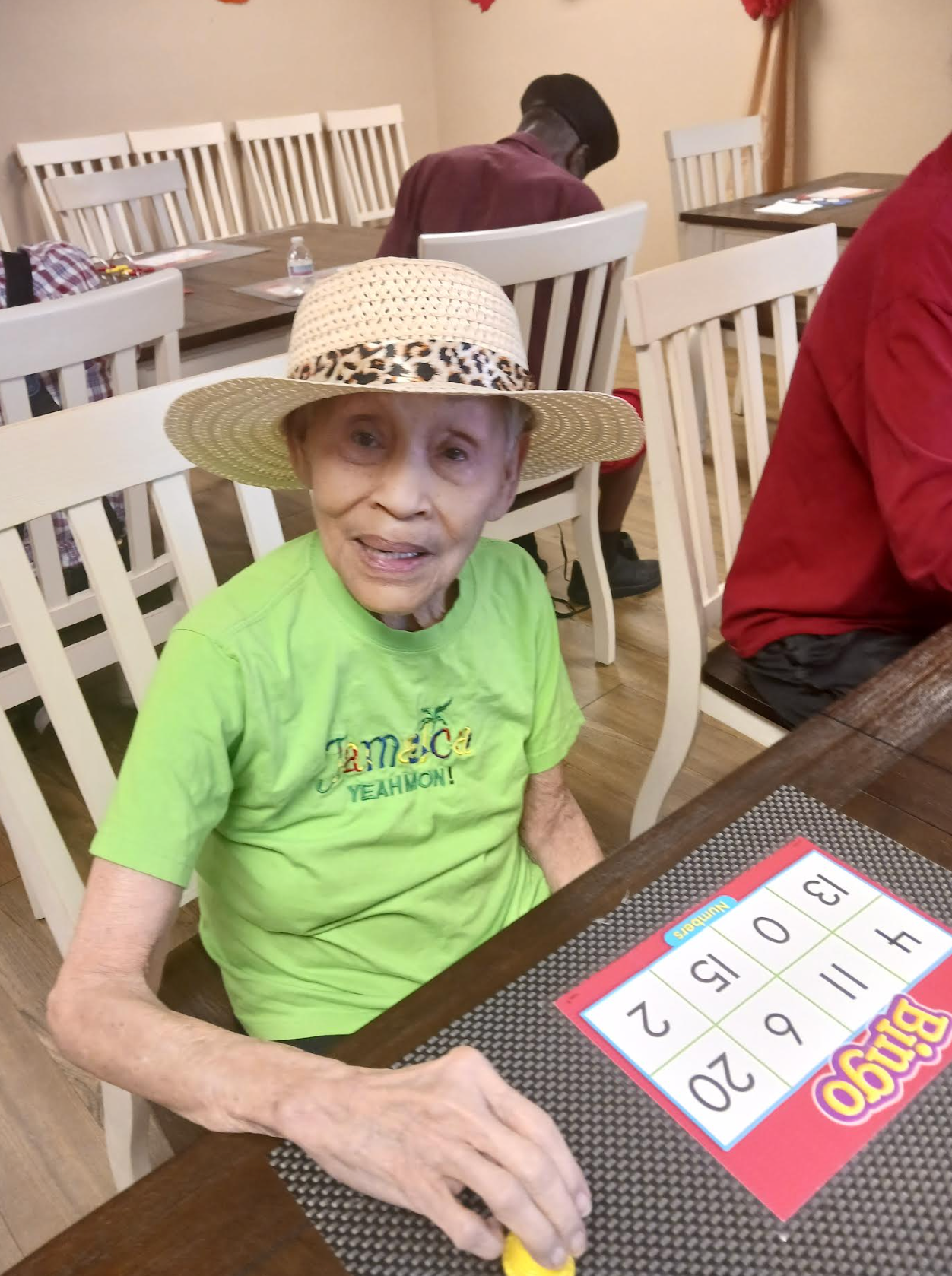 An elderly woman is sitting at a table playing bingo.
