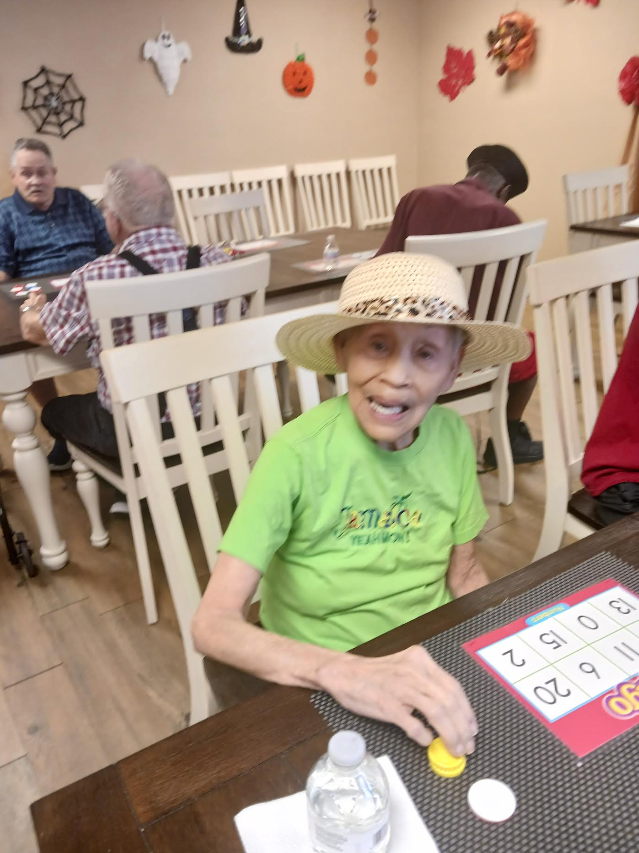 An elderly woman in a green shirt is playing bingo