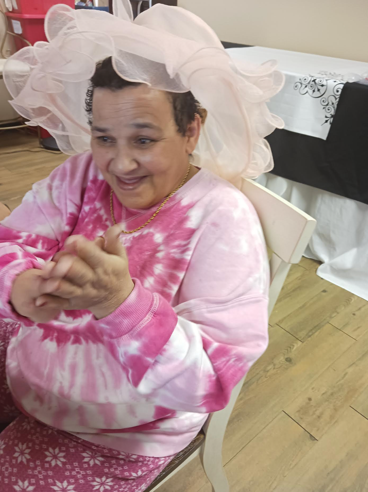 A woman wearing a pink hat is sitting in a chair.