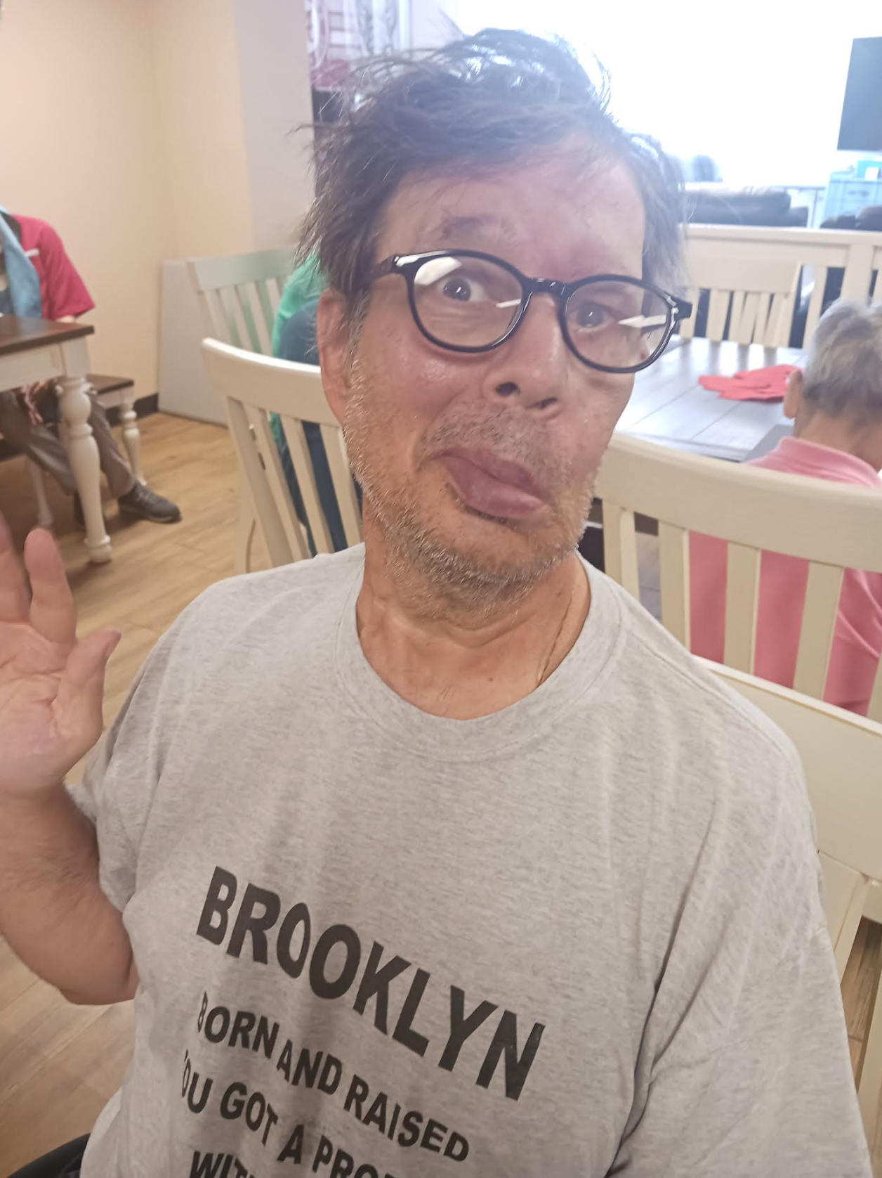 A man wearing a brooklyn born and raised t-shirt is making a funny face.