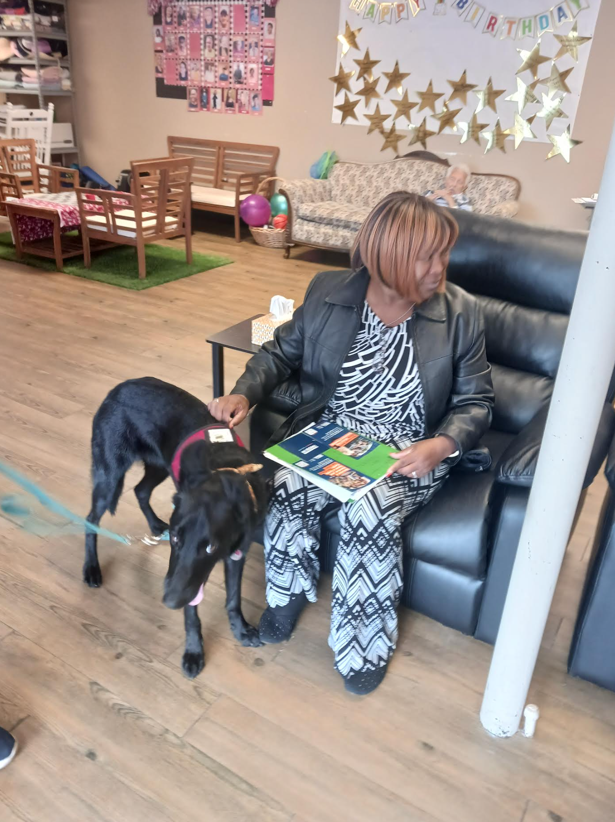 A woman is sitting on a couch with a book and a dog