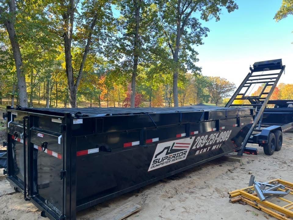 Black Superior Dumpster Rentals 20-yard roll off dumpster trailer parked on a residential property in Southwest Michigan, ready for a home renovation or cleanup project.