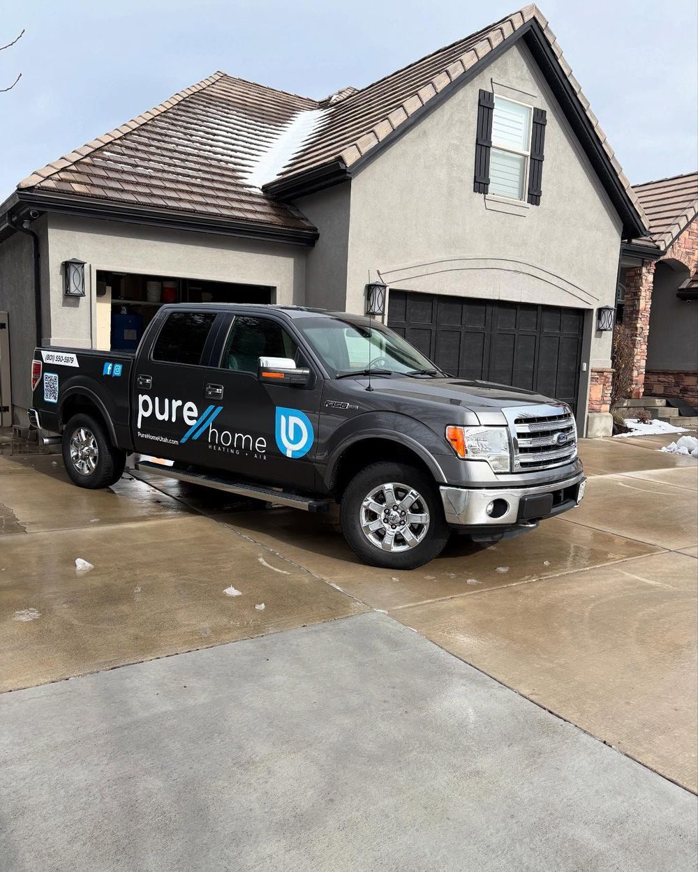 Dark gray Pure Home truck parked in front of a light gray house. Dark gray Pure Home truck parked in front of a light gray house.