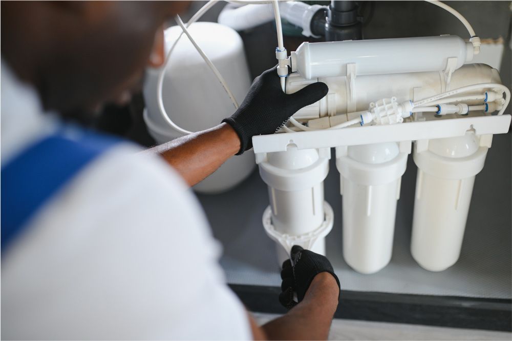 Person in black gloves installing or repairing a water filtration system.