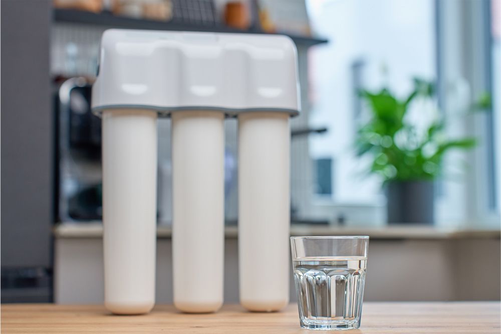 White water filter system and a glass of water on a wooden table. White water filter system and a glass of water on a wooden table.