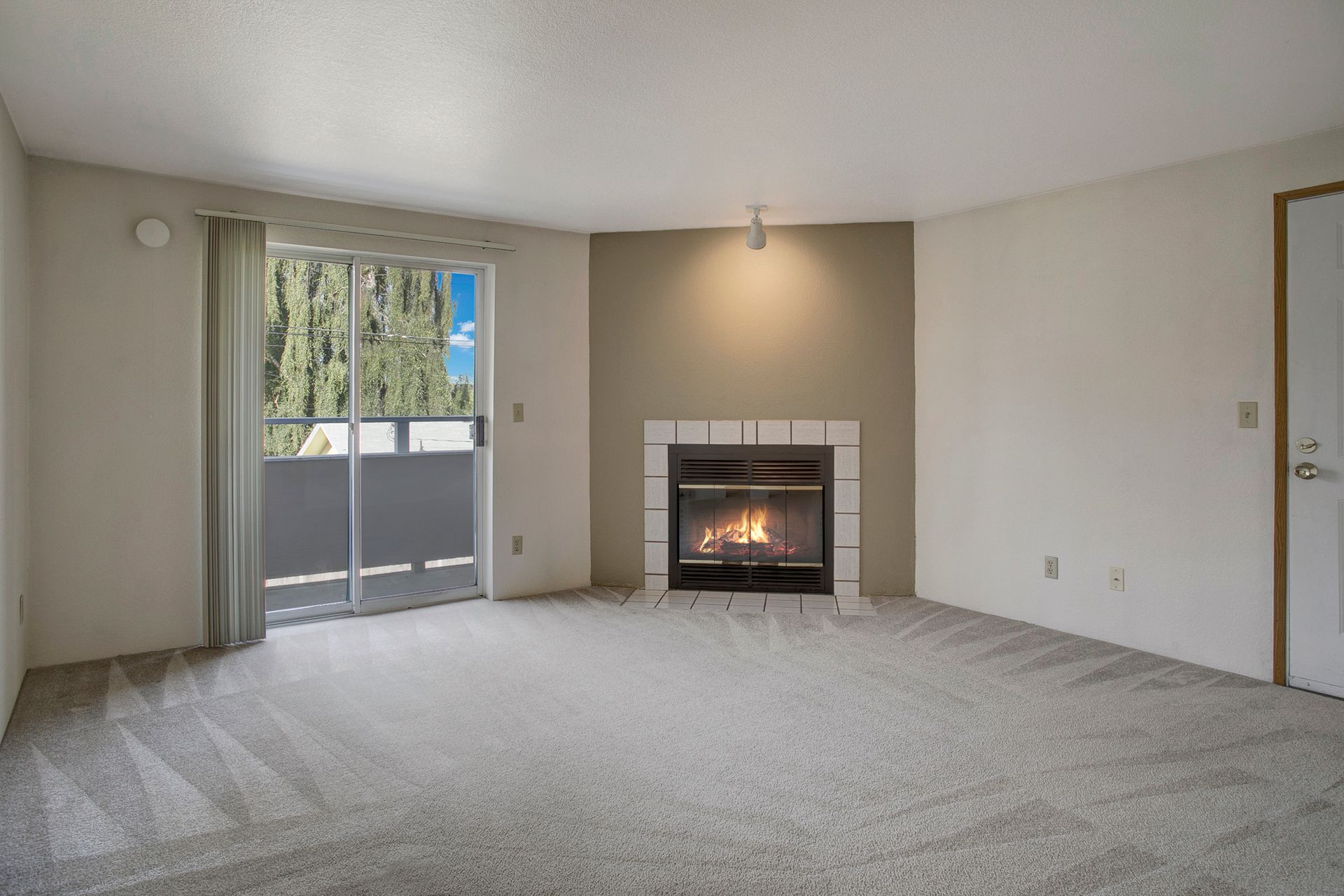 An empty living room with a fireplace and sliding glass doors
