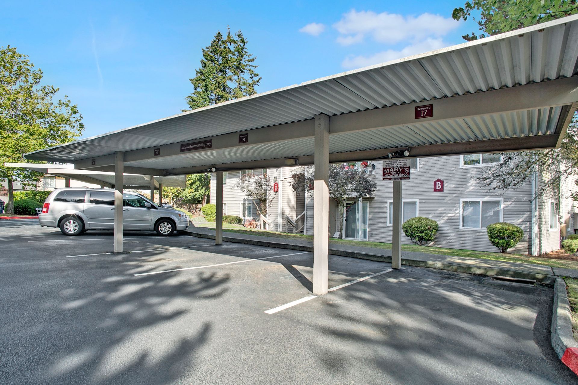 A car is parked under a canopy in a parking lot.