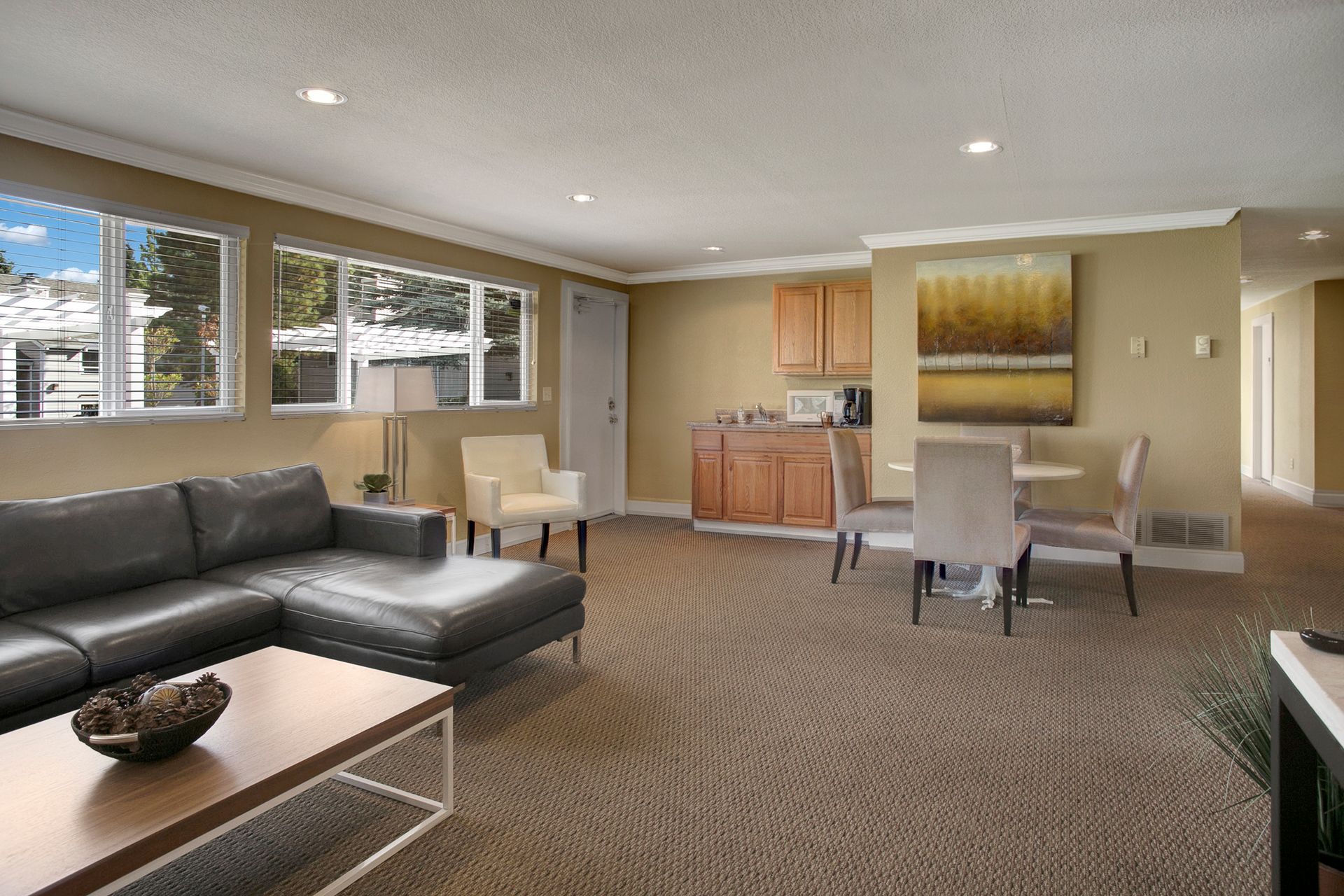 A living room with a couch , table , chairs and a painting on the wall.