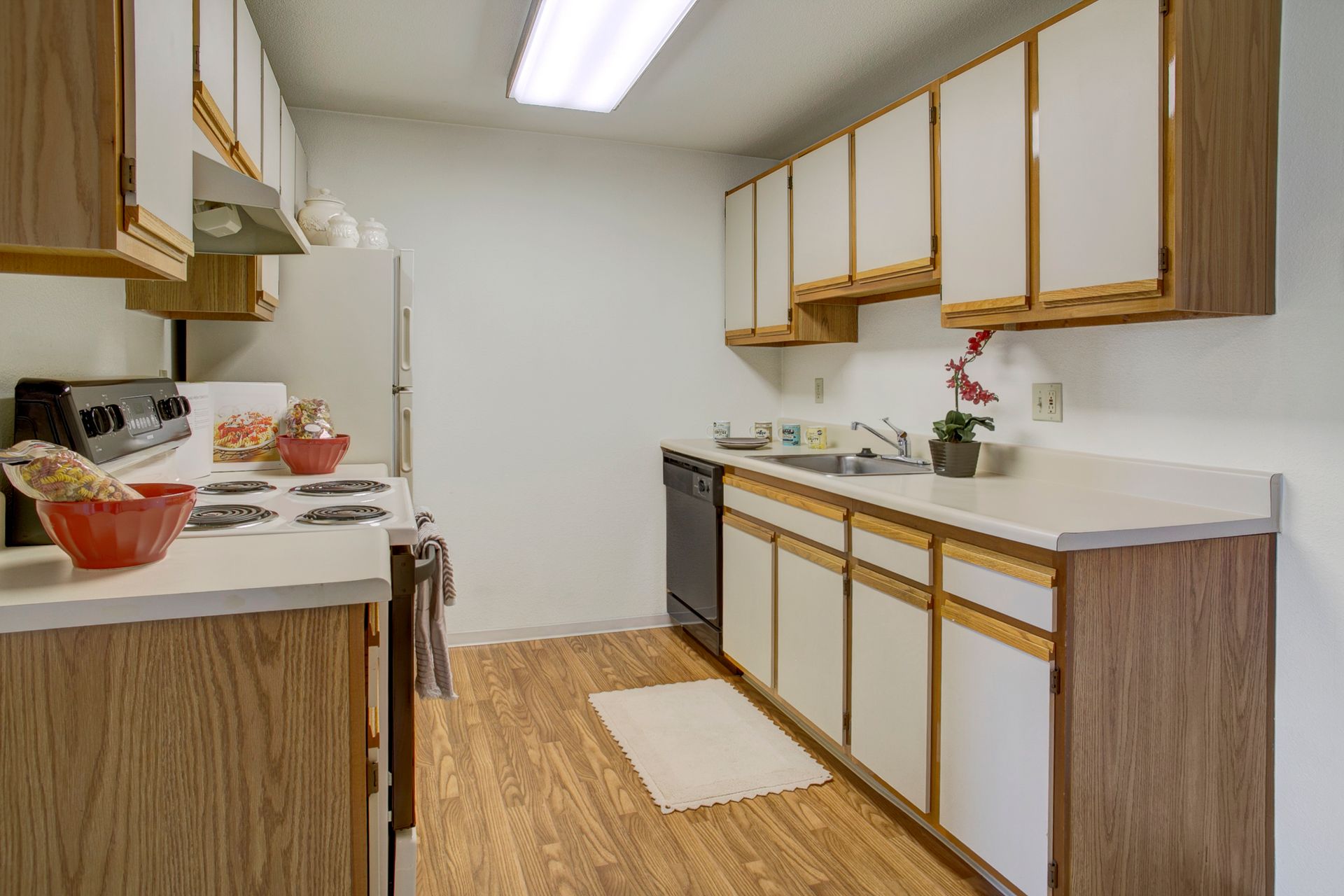A kitchen with wooden cabinets , a stove , a refrigerator , and a sink.