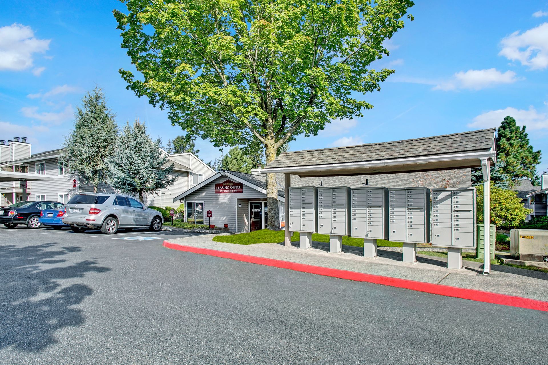 A parking lot with cars parked in front of a building and a tree.