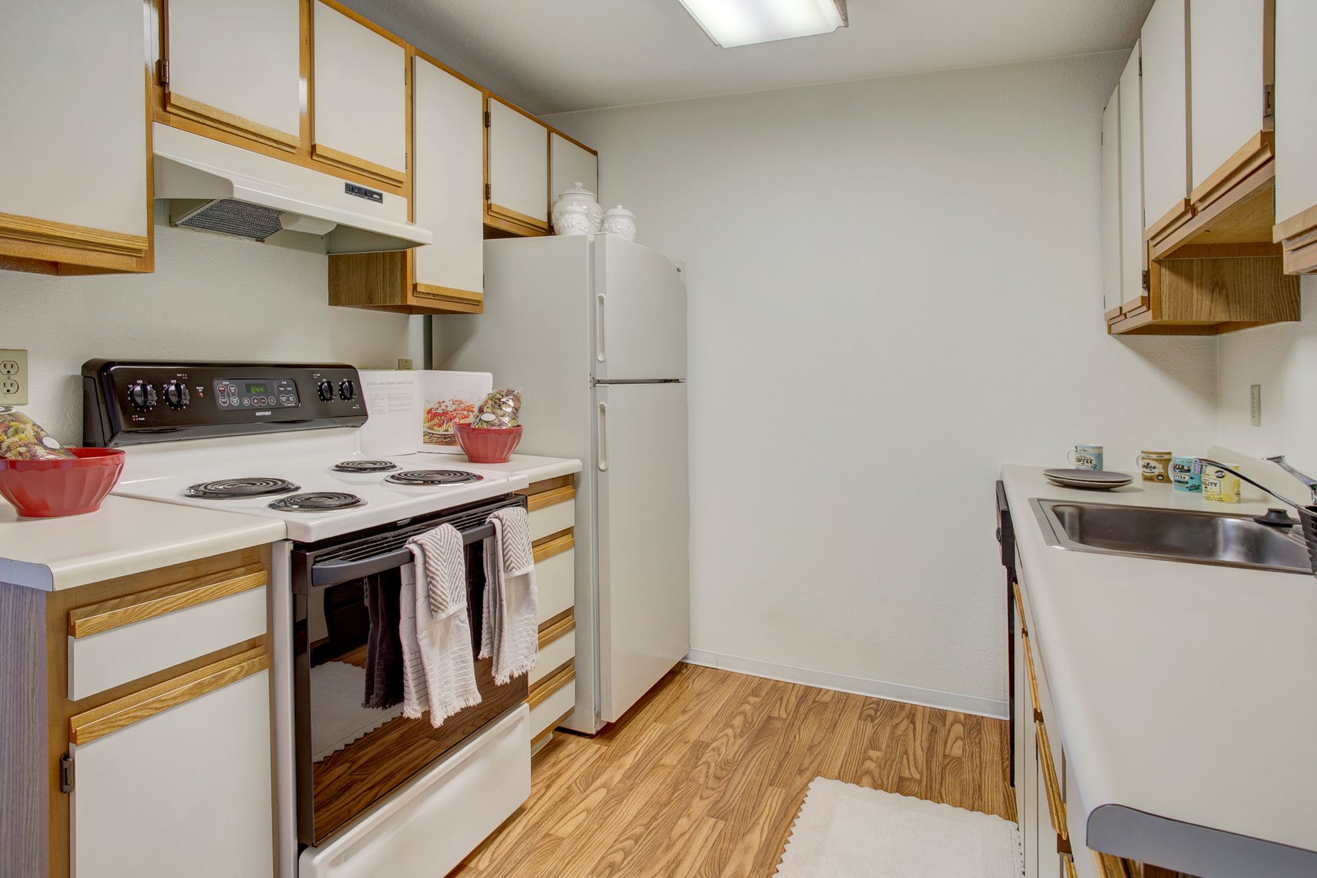 A kitchen with a stove , refrigerator , sink and cabinets.