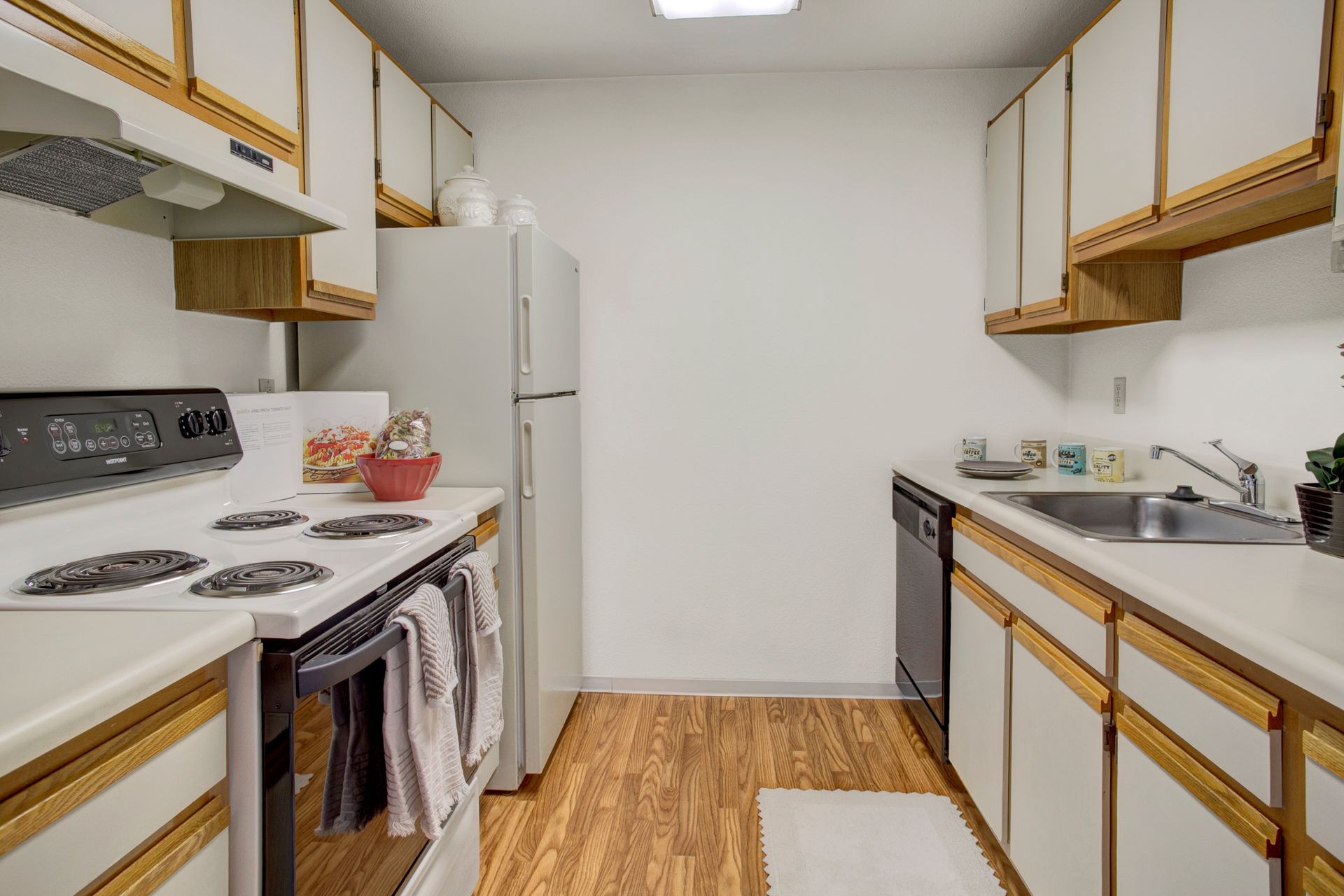 A kitchen with a stove , refrigerator , sink and dishwasher.